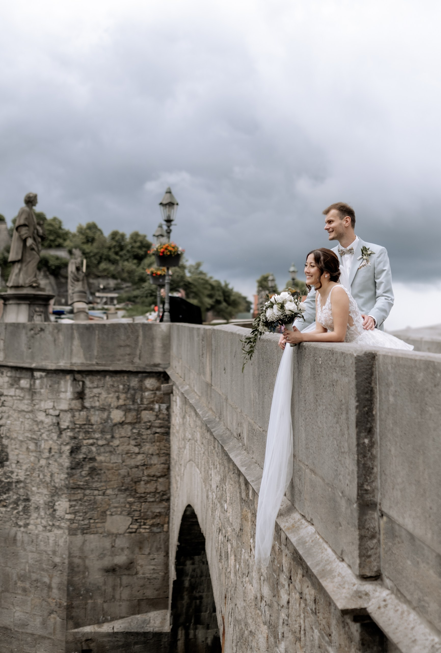 timmungsvolles Porträt: Das Brautpaar blickt gemeinsam in die Ferne, während im Hintergrund die Sonne über der Würzburger Skyline untergeht