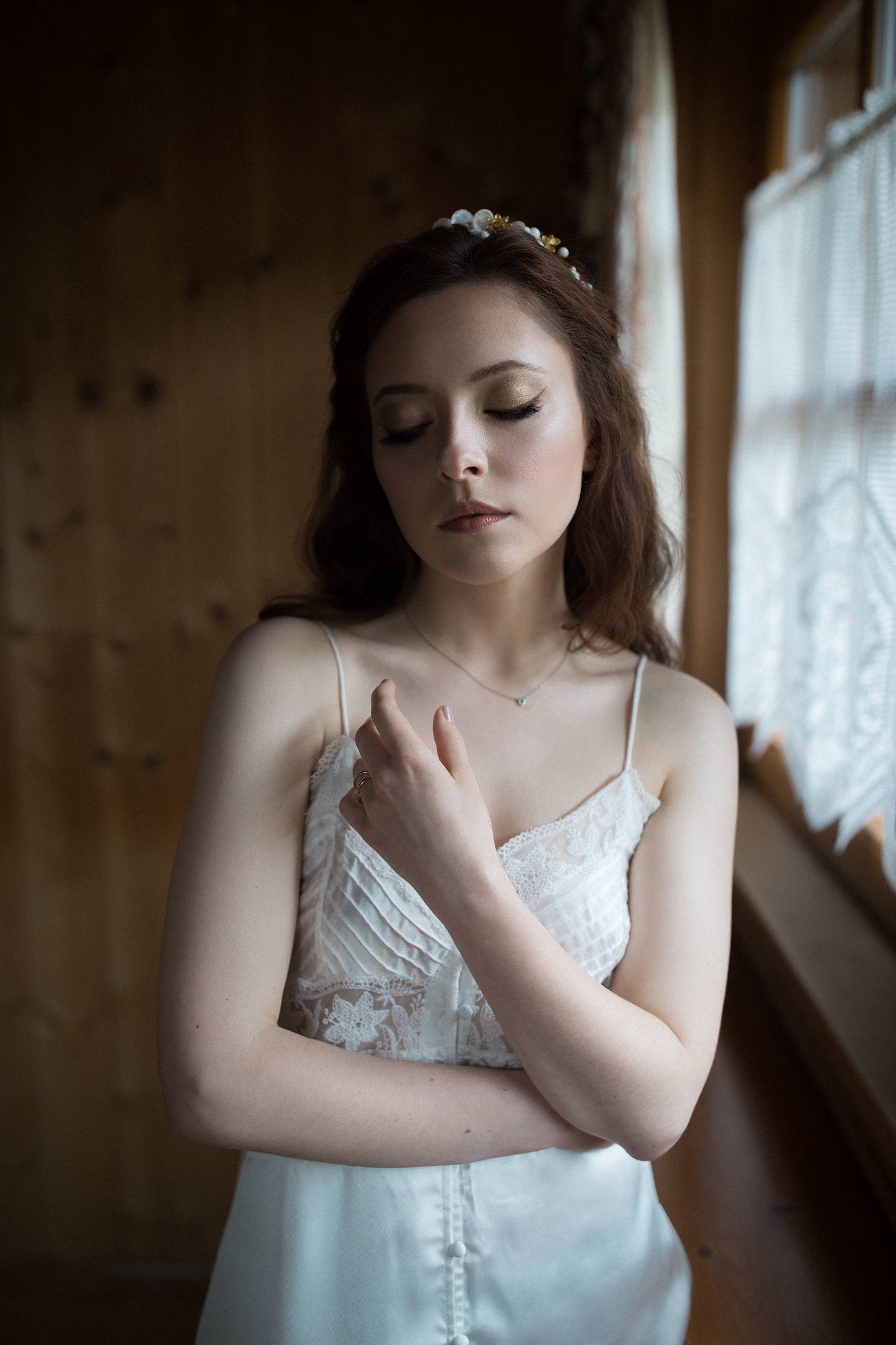 Braut im Seidenkleid am hölzernen Fensterlicht