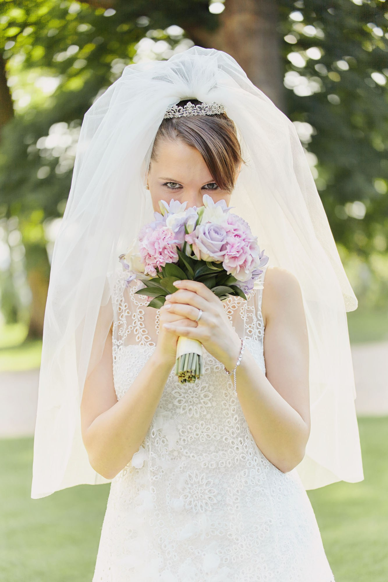 Captured in a moment of happiness, the bride smells her bouquet while posing at Chateau Mcely, Czechia, after her outdoor nuptials.