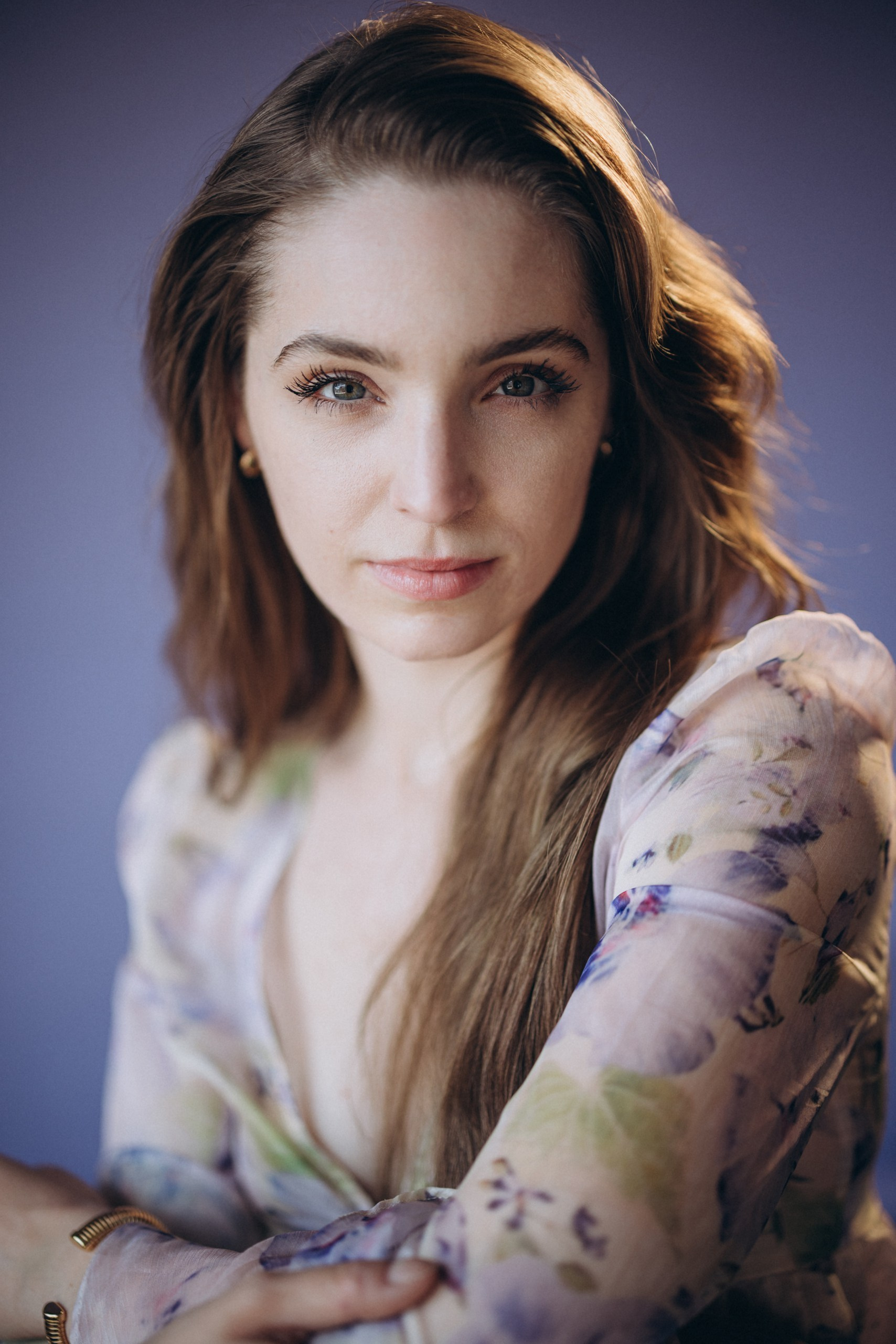 Actor headshot of a serious woman in a floral blouse, with soft lighting and a neutral background
