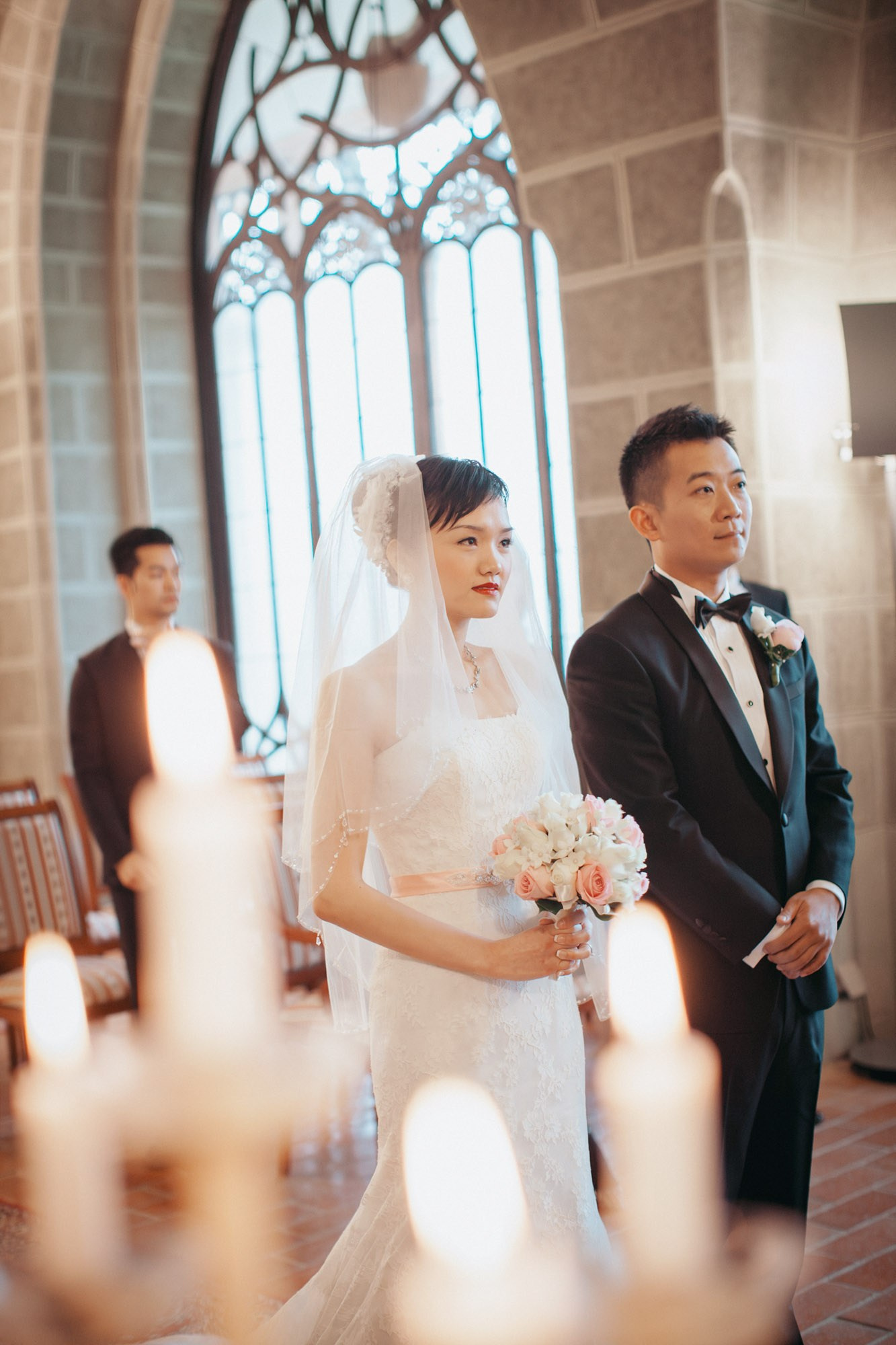 A bride & groom from Hong Kong listen intently to the wedding officiant during their candlelit ceremony at the State Chateau of Hluboka.
