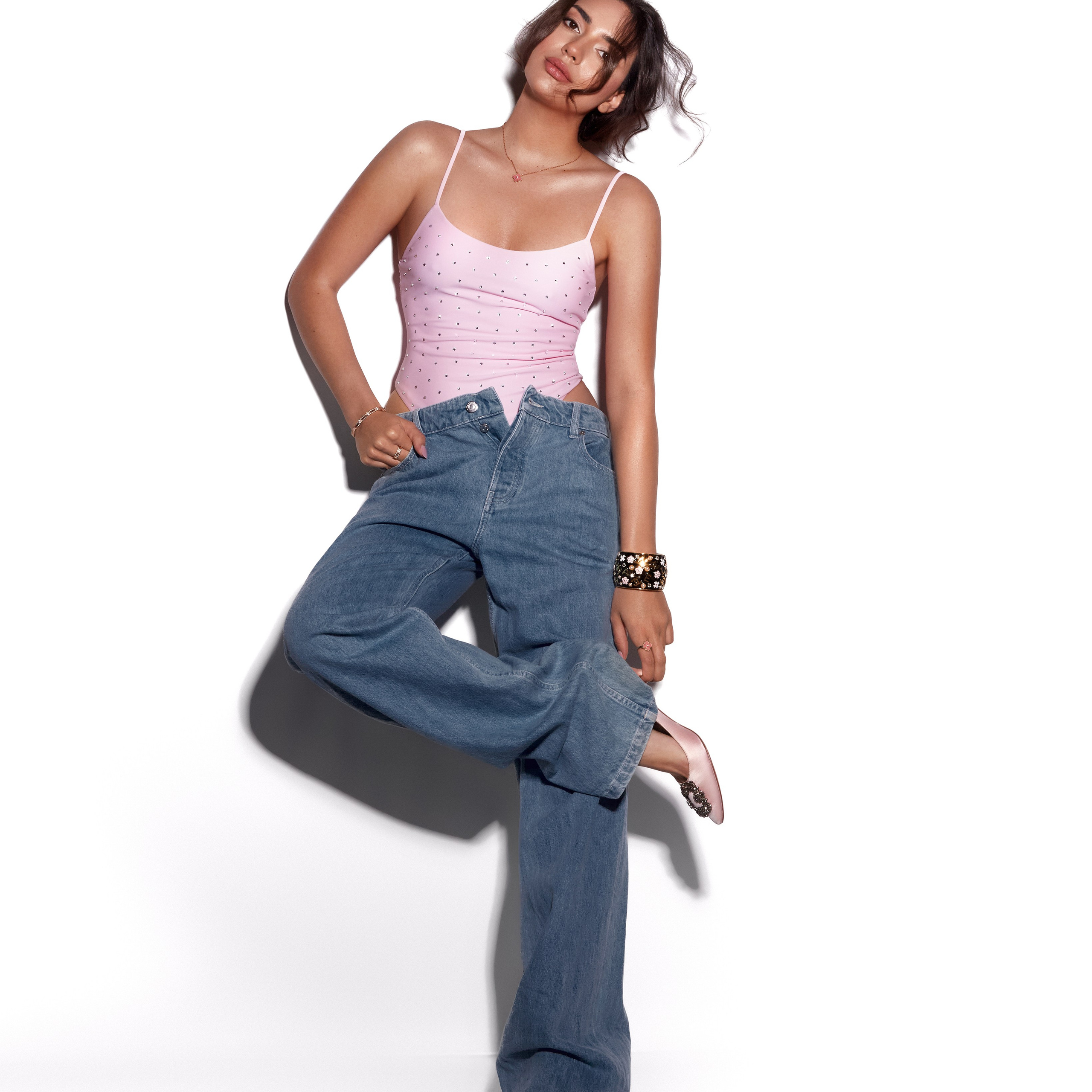 Fashion photographer Hanna Asaulova | Stylish model in a pink top and wide jeans in a relaxed pose on a white background, fashion photoshoot in Vilnius.