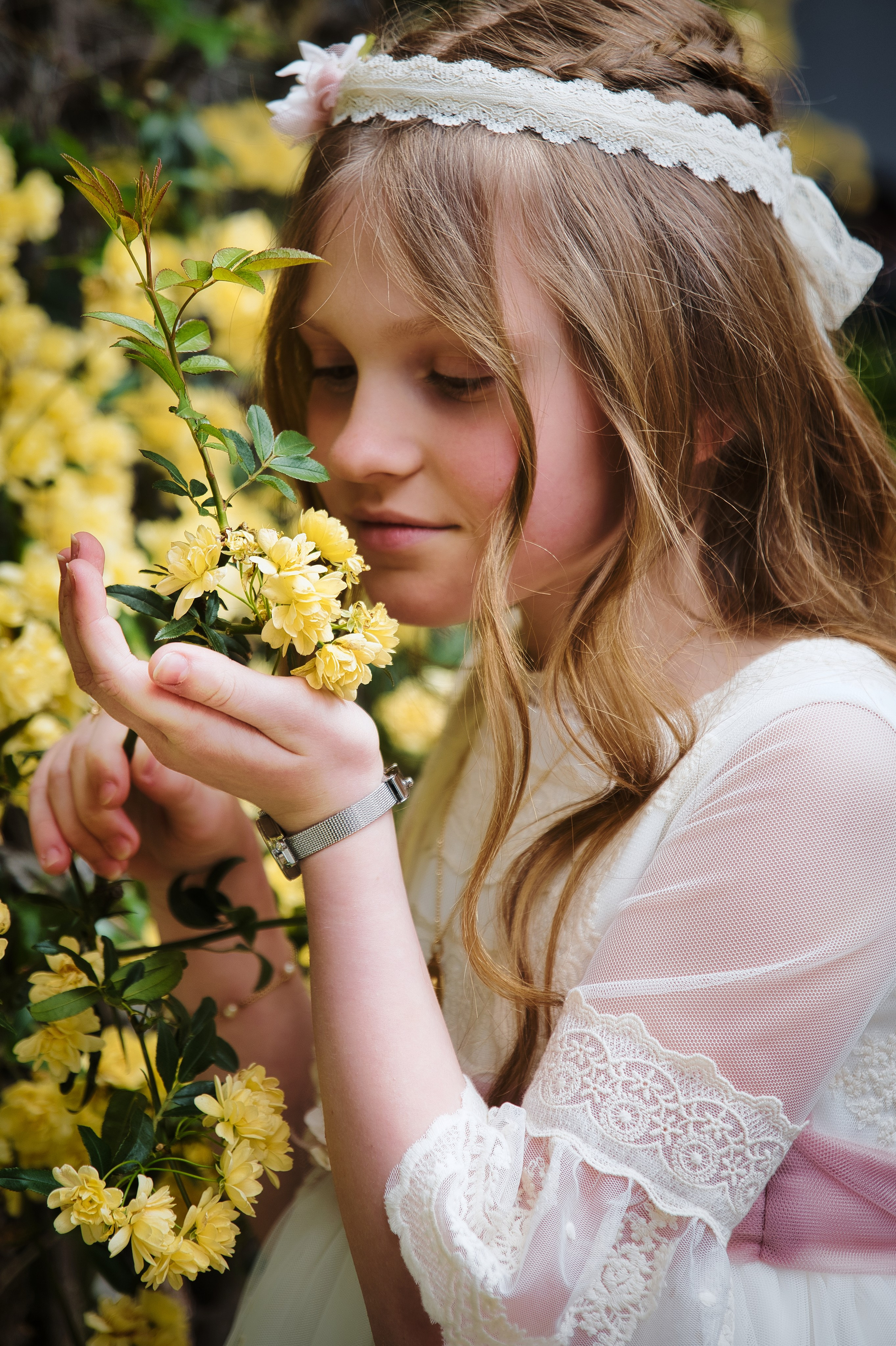 foto de niña de comunion sujetando y oliendo una flor