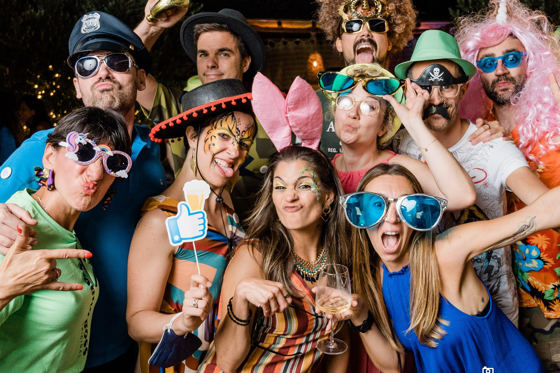 Gruppo allegro di amici in festa, con accessori colorati e divertenti, festeggiano in uno scatto vivace e pieno di energia, immortalati dal servizio fotografico matrimoniale in una scena di pura gioia e spensieratezza con photo booth e stampa immediata