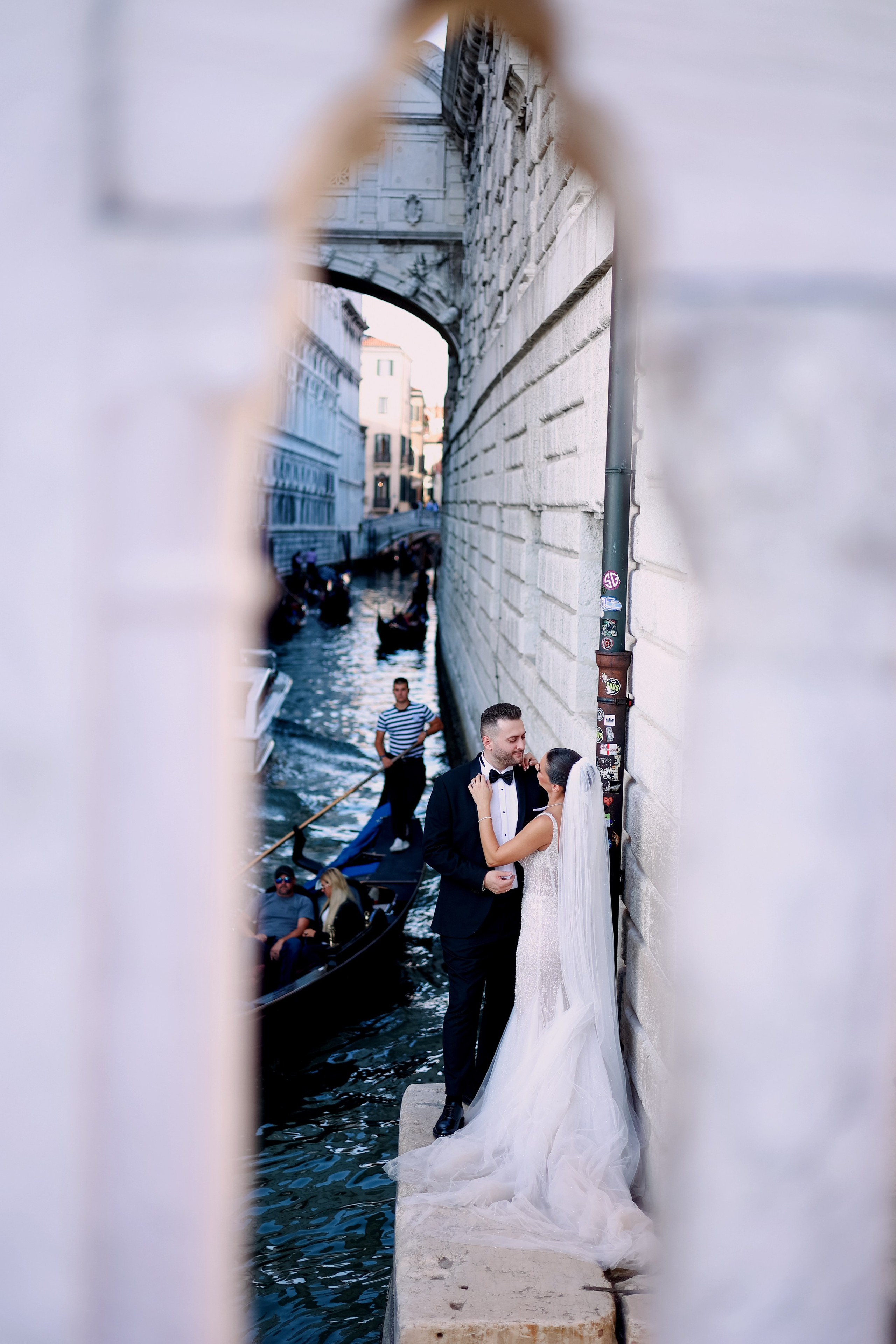 Romantic wedding couple in Venice standing beside a gondola near the canals and the Bridge of Sighs