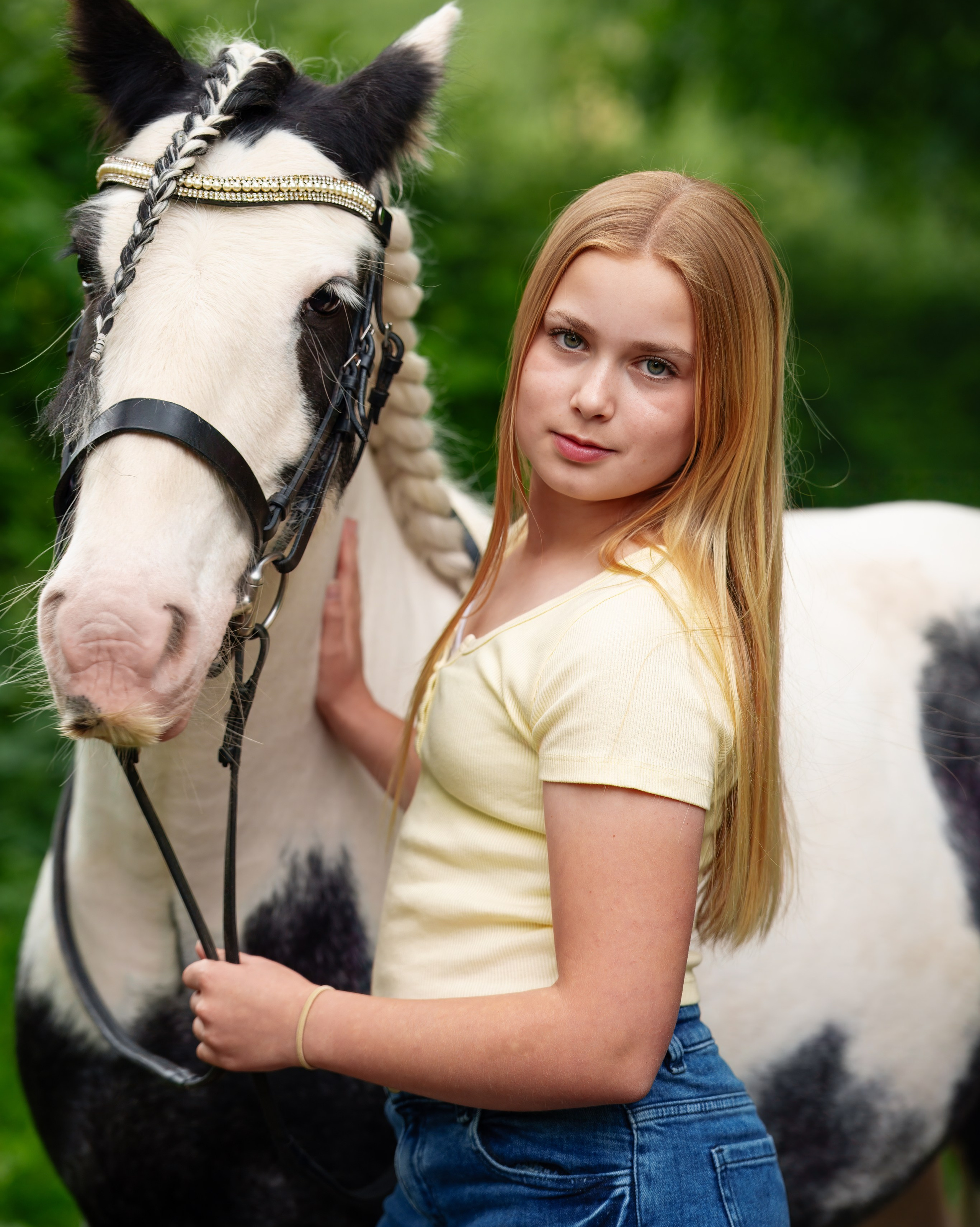 Teen girl holding horse’s halter during soft evening light equestrian portrait