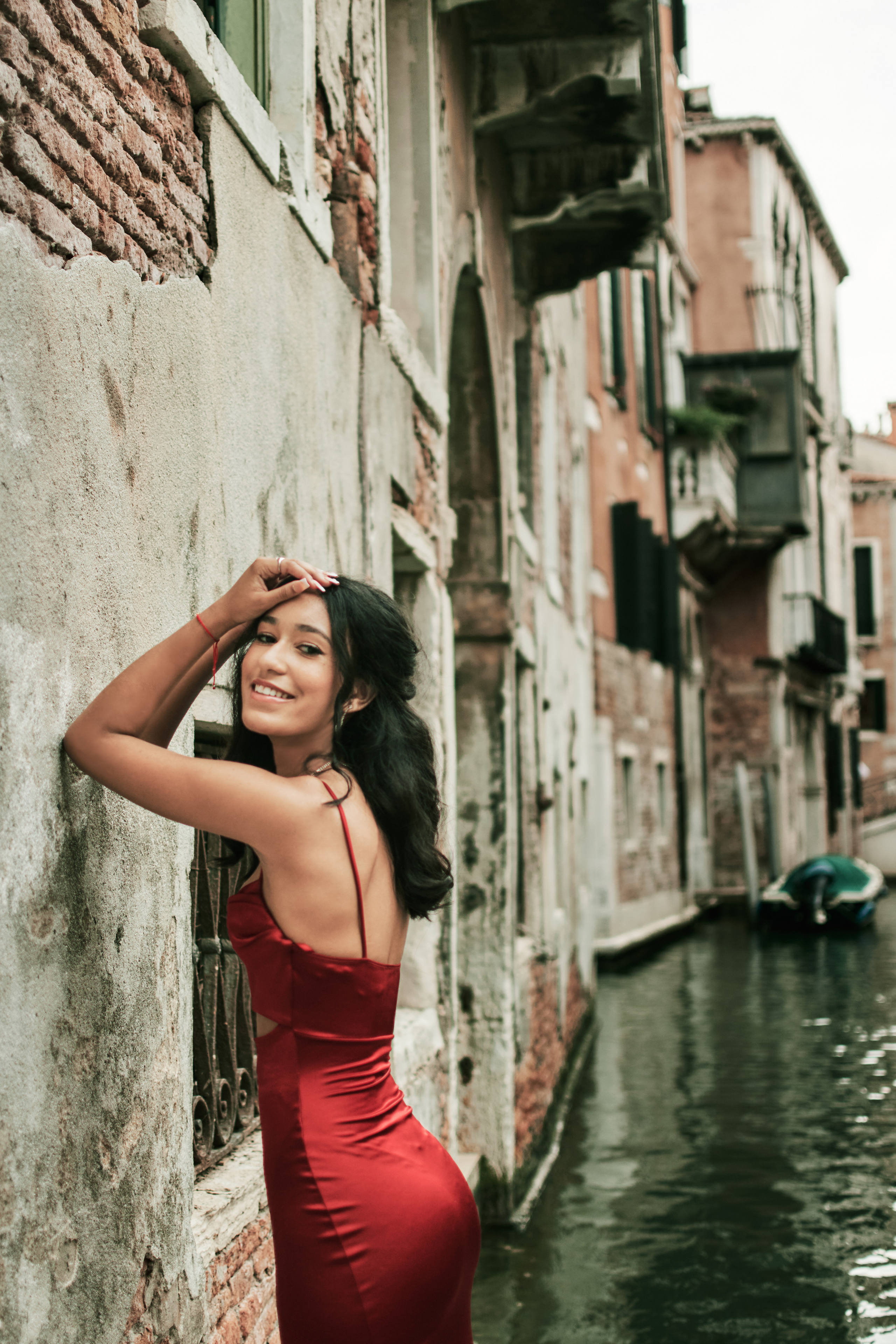 Venice's narrow canals serve as a captivating backdrop for a girl in a red dress, radiating charm.