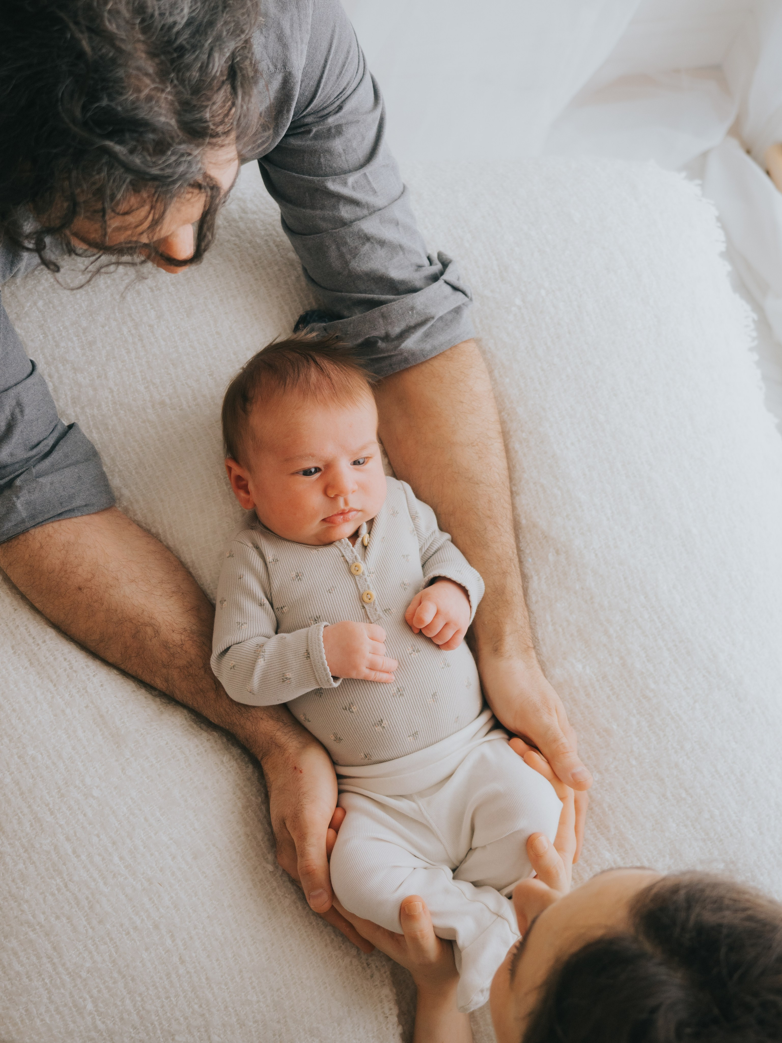 Nouveau-né regardant ses parents qui la tiennent.