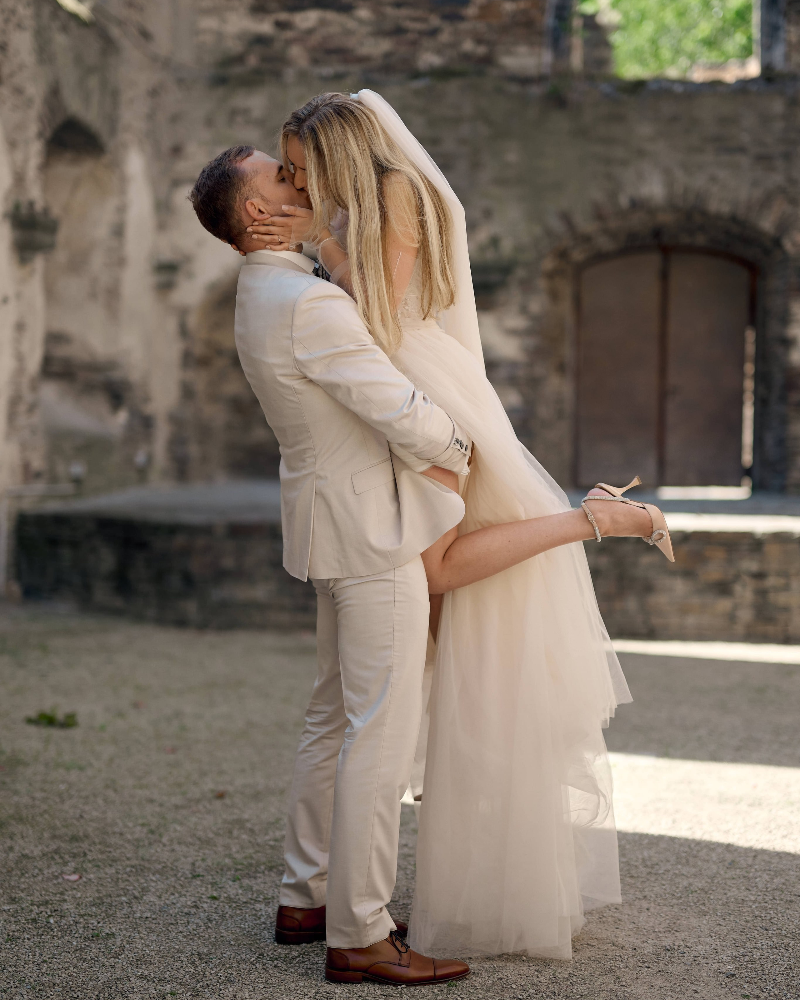 Bräutigam hebt seine Braut hoch und küsst sie liebevoll bei einem Hochzeitsshooting in einer romantischen Ruine nahe Bonn, fotografiert von Hochzeitsfotograf Alex Fetter.