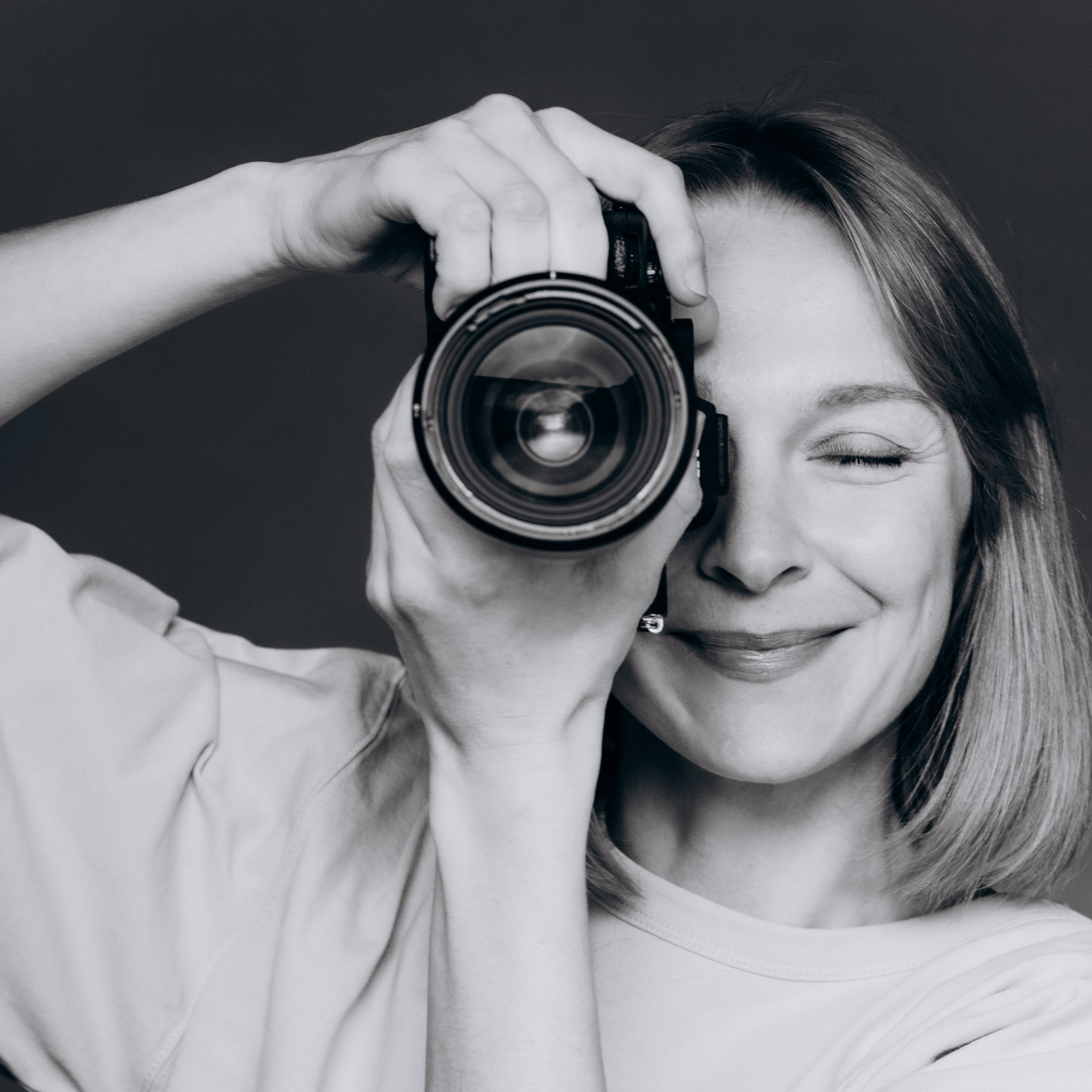 Porträt einer lächelnden Fotografin mit Kamera im Studio – authentische Momentaufnahme für professionelle Foto Sessions, Familienfotografie und natürliche Portraits.