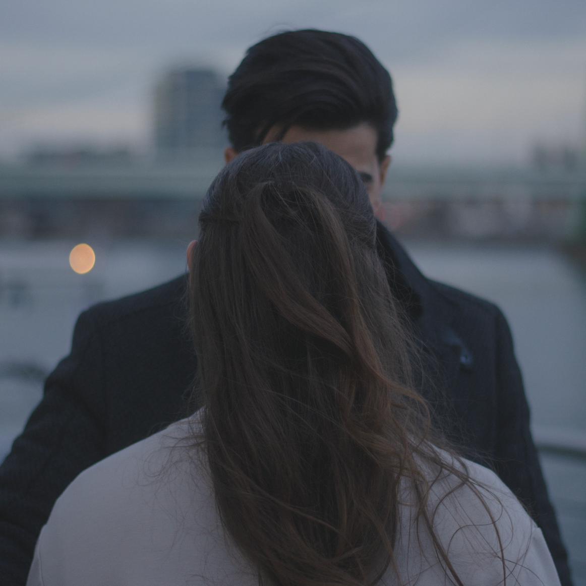 Paarfoto ohne Gesicht mit dreamy look und weichen Tönen vor einem Fluss