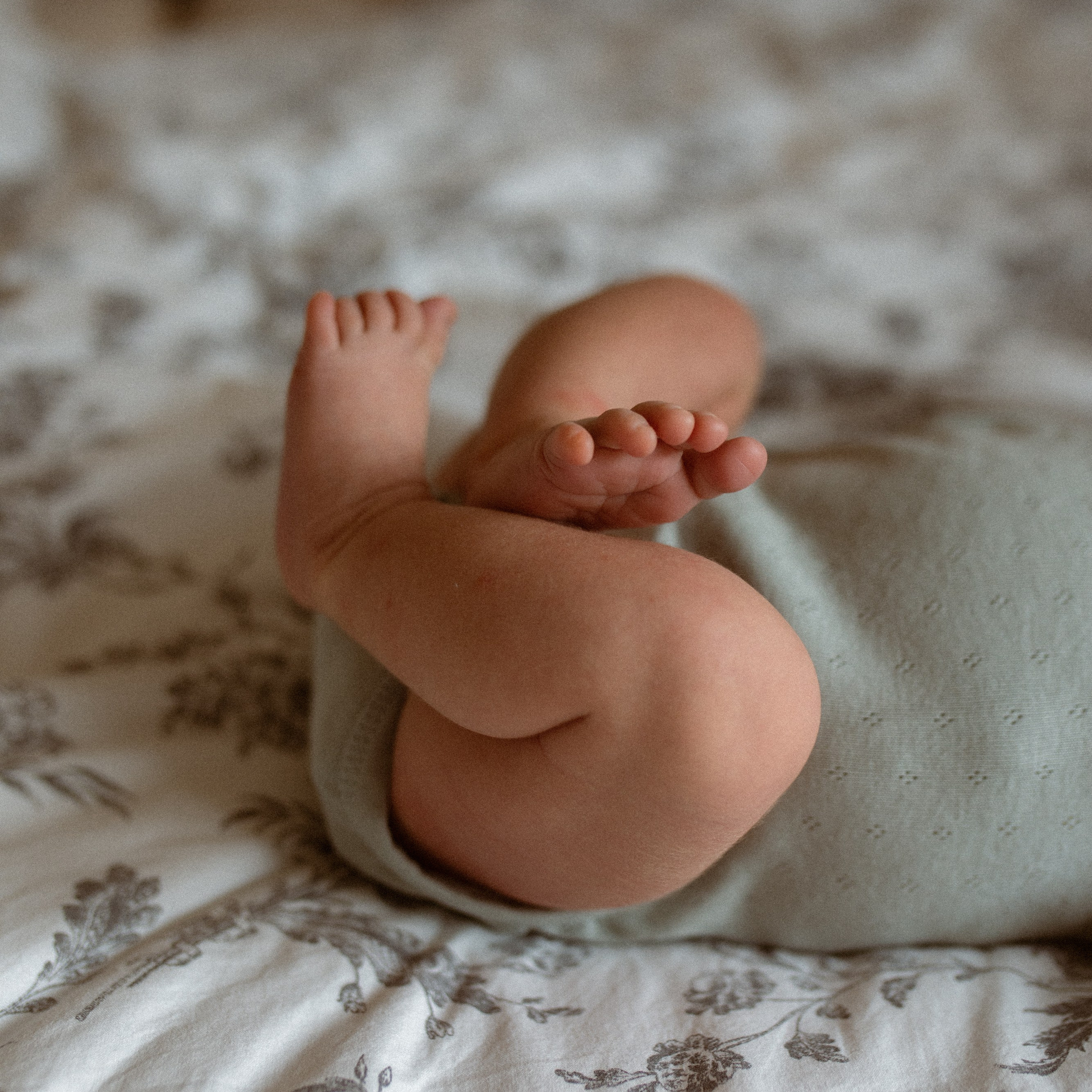 Babyfotos von Vater und Kind beim Kuscheln auf dem Bett beim Babyshooting.
