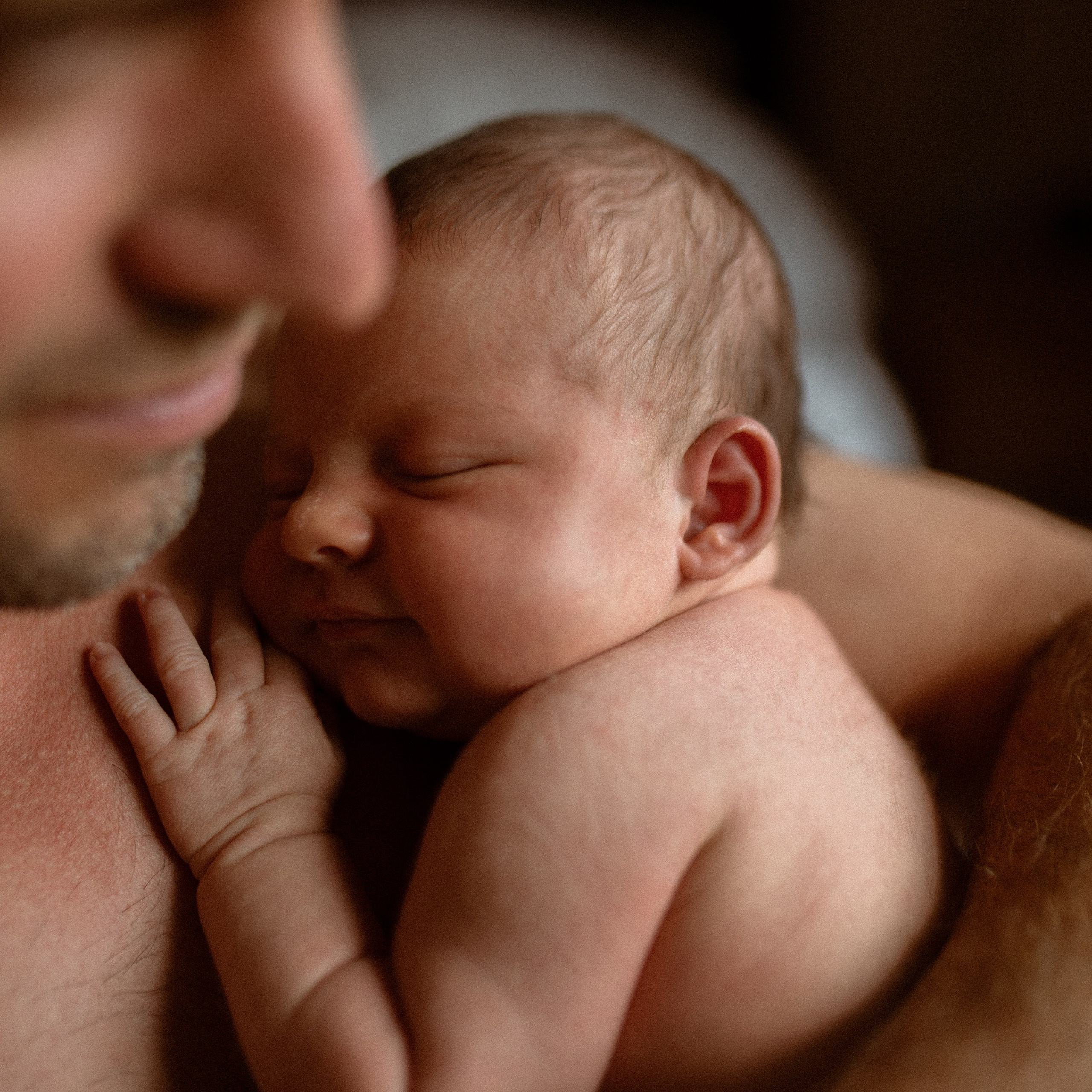 Babyfotos von Vater und Kind beim Kuscheln beim Newborn Babyshooting.