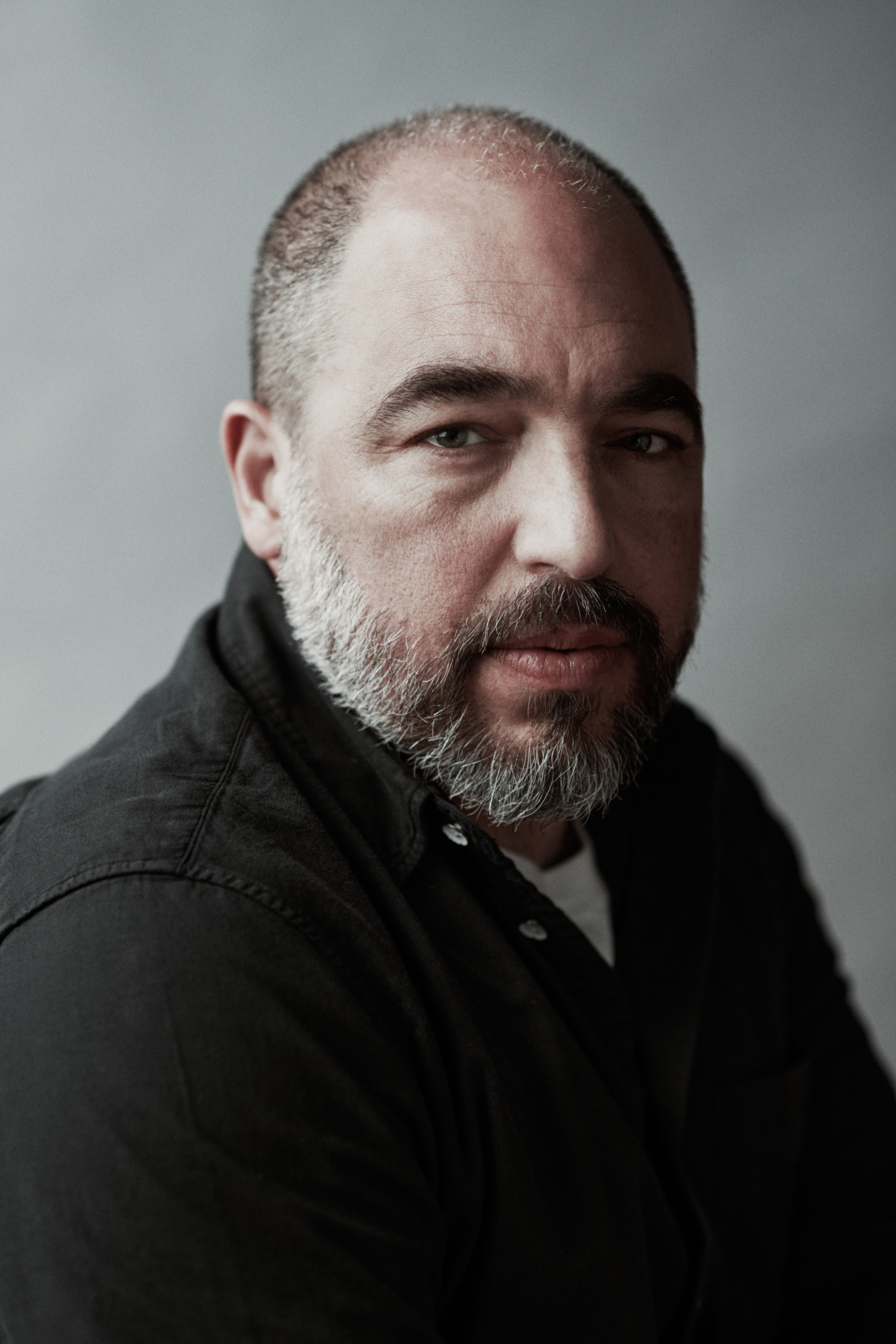 A portrait photograph of a man with a beard on a gray background, the photoshoot for Netflix  in Amsterdam  