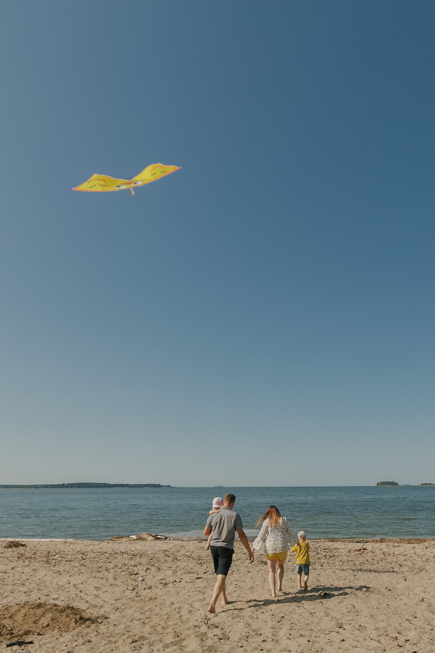Padres con hijos vuelan una cometa amarilla a la orilla del mar en Valencia