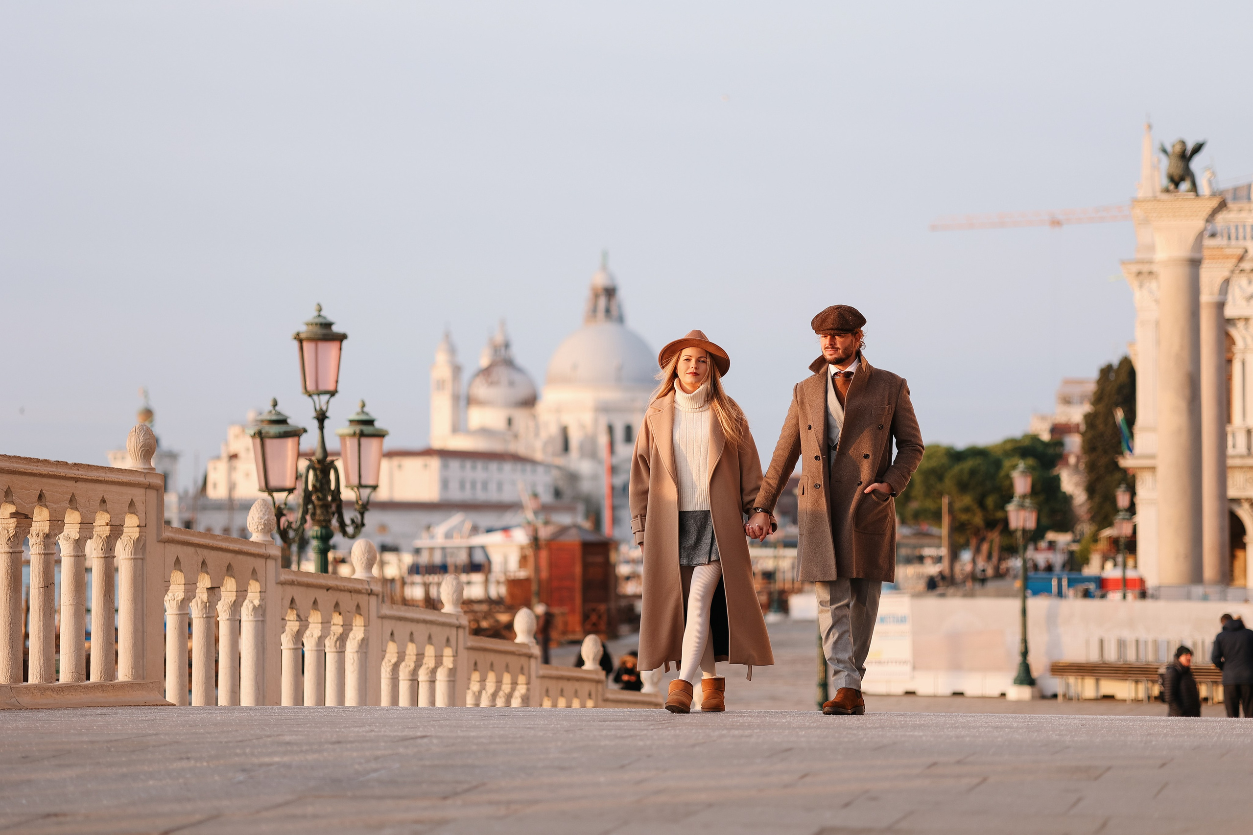 A couple embracing on a stone bridge in Venice during winter