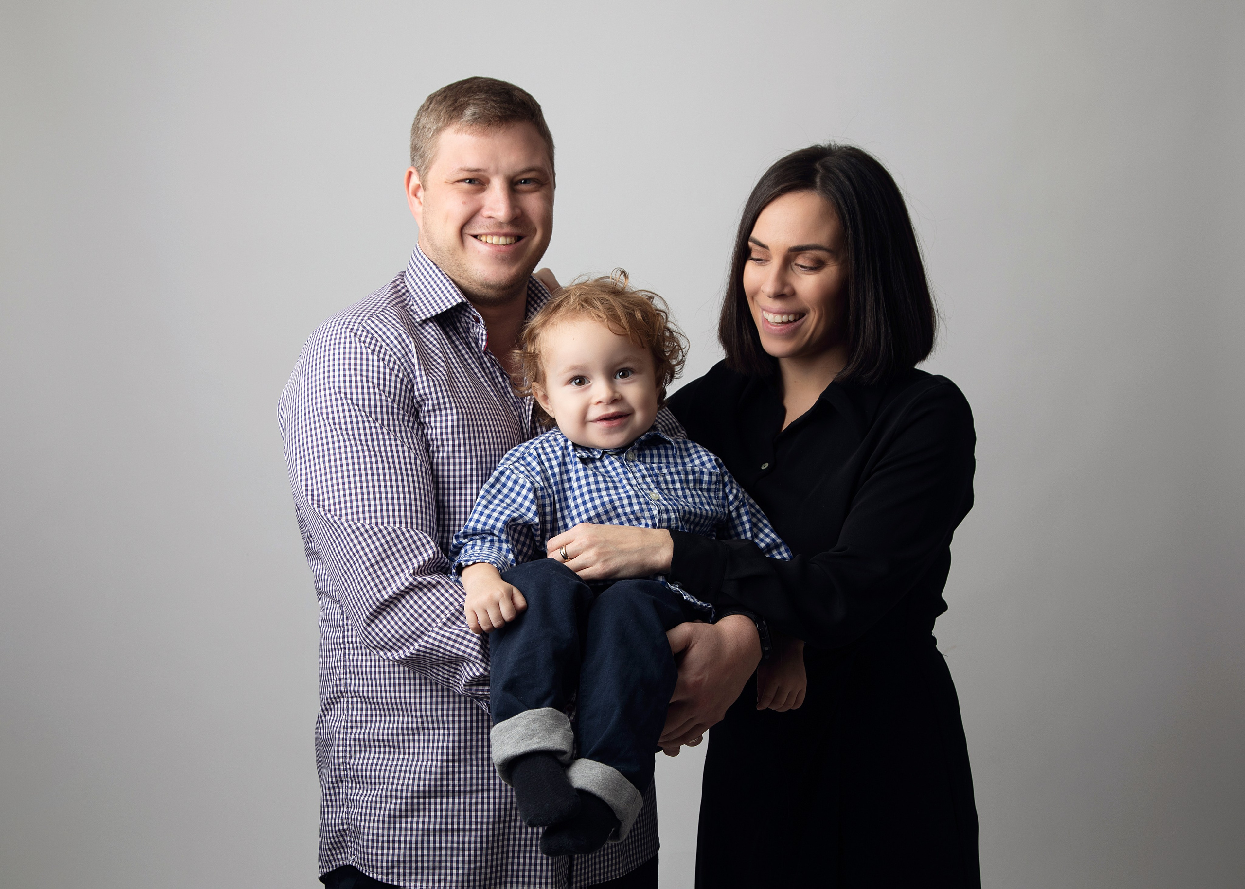 Familjefotografering i studion fångar ögonblicket av lycka med barn, mamma och pappa tillsammans.