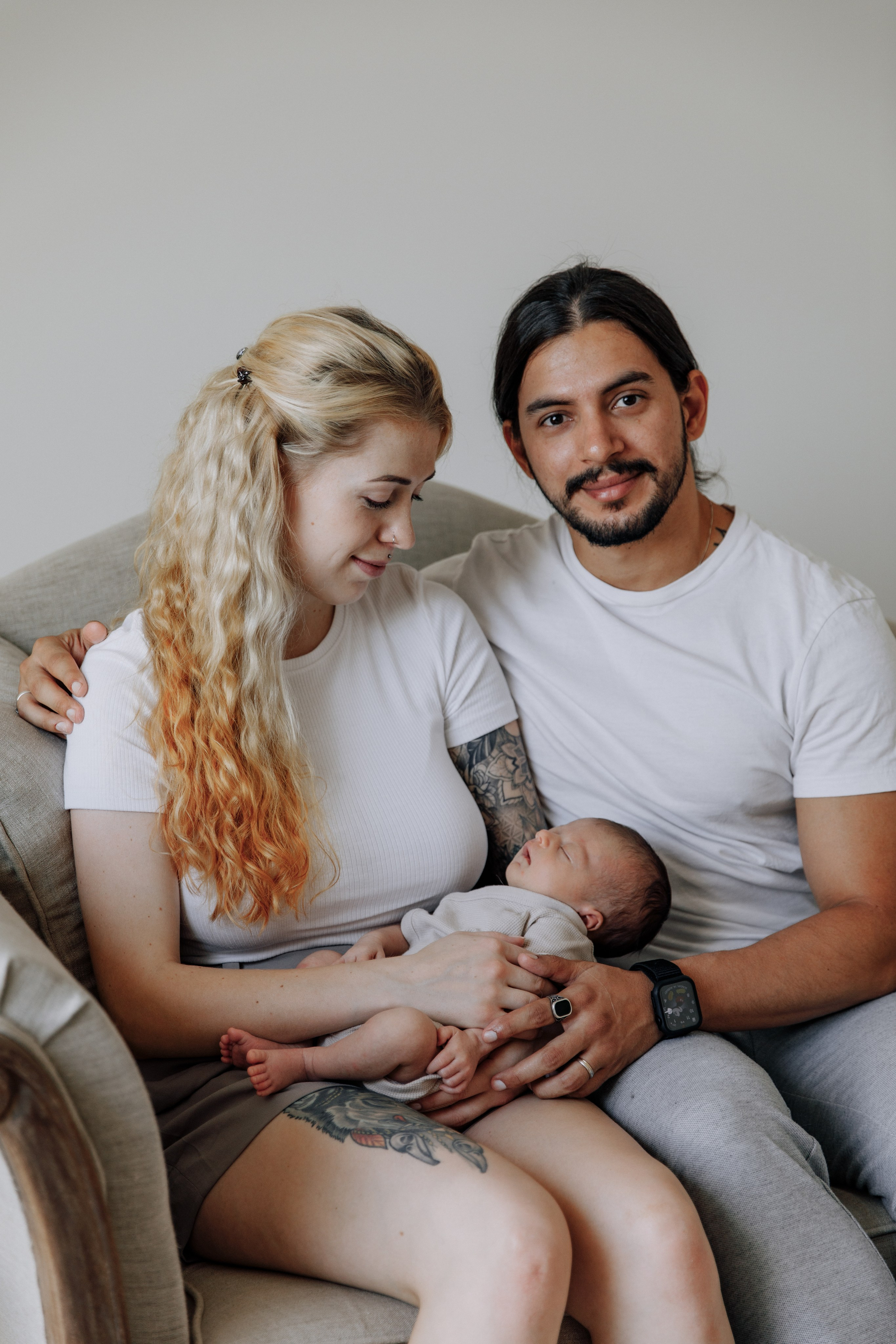 Eltern halten ihr Baby liebevoll in den Armen. Ein zärtlicher und familiärer Moment.