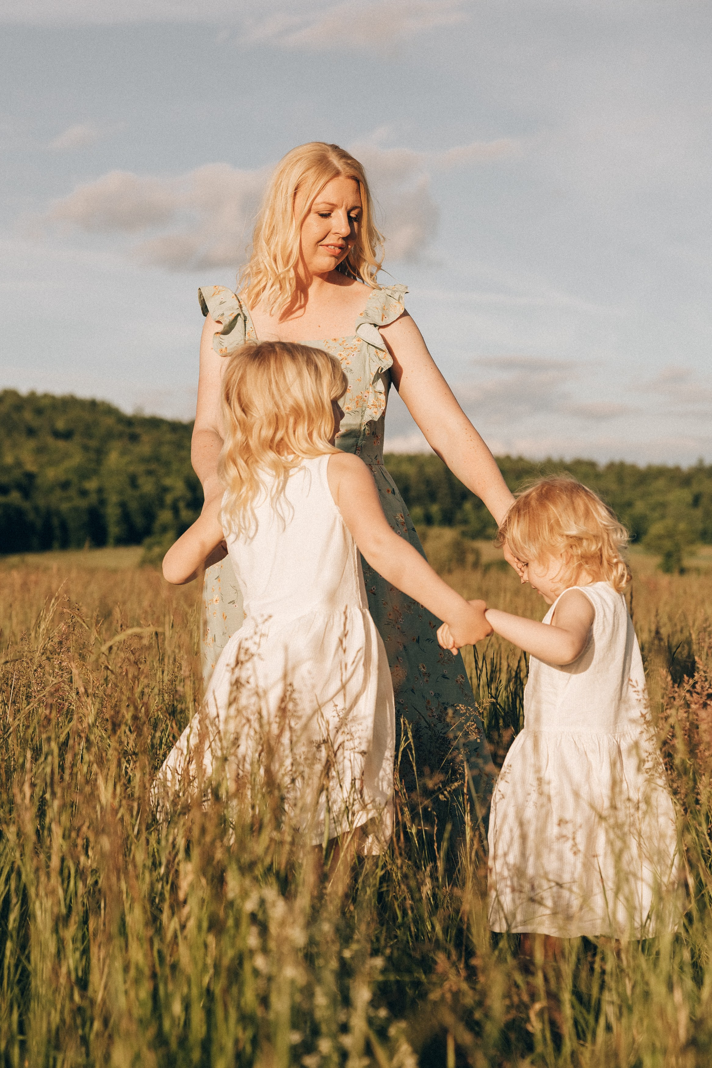 Family photoshoot in a daisy meadow at golden hour — natural light, warm tones, candid moments between a mother and her daughters. Lifestyle and Family Photographer in Pisek Oxana Telupilova
