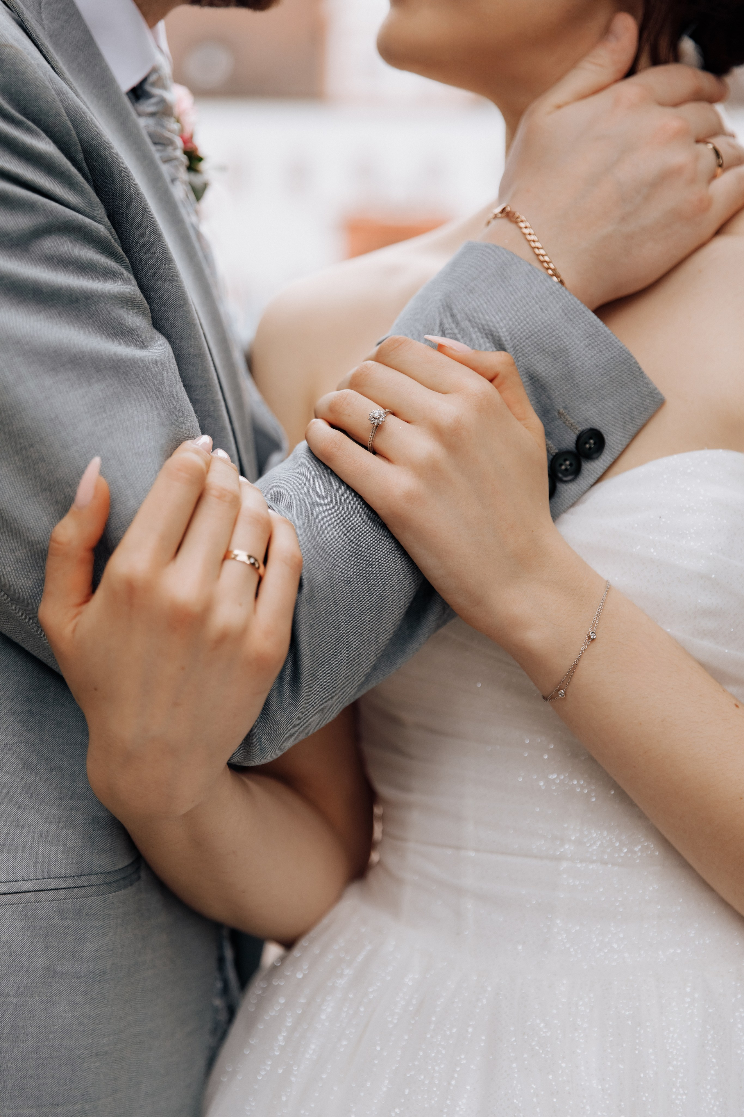 Die Hand des Bräutigams liegt auf dem Nacken der Braut, während ihre Hände seinen Unterarm umarmen.