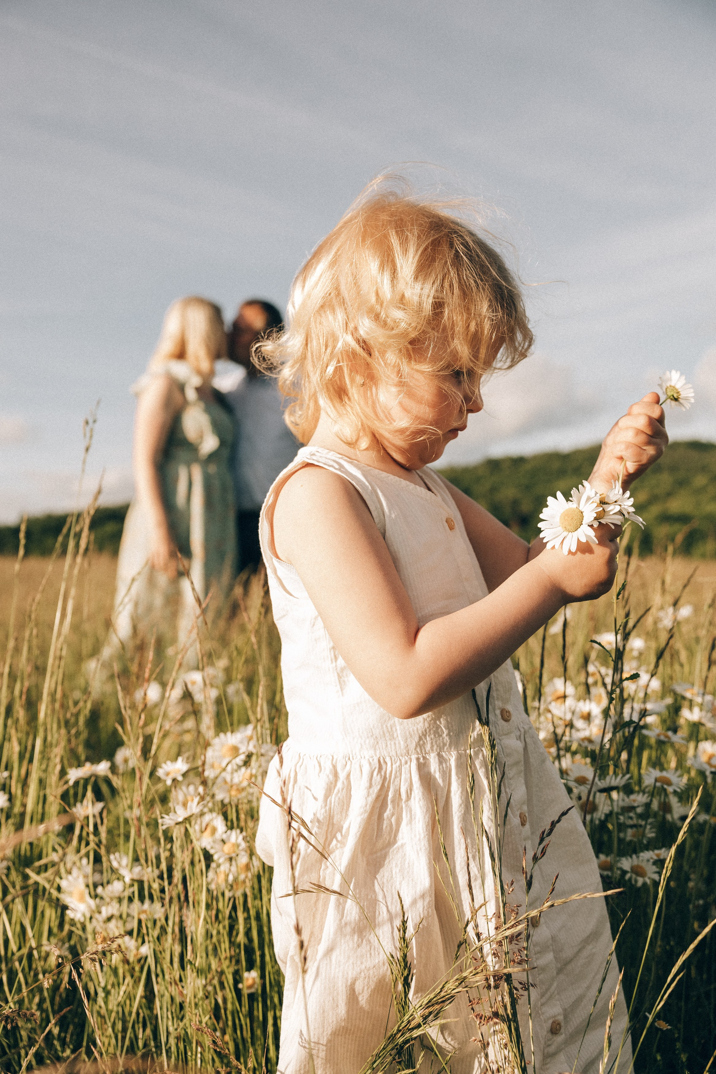 Family photoshoot in a daisy meadow at golden hour — natural light, warm tones, candid moments between a mother and her daughters. Lifestyle and Family Photographer in Pisek Oxana Telupilova
