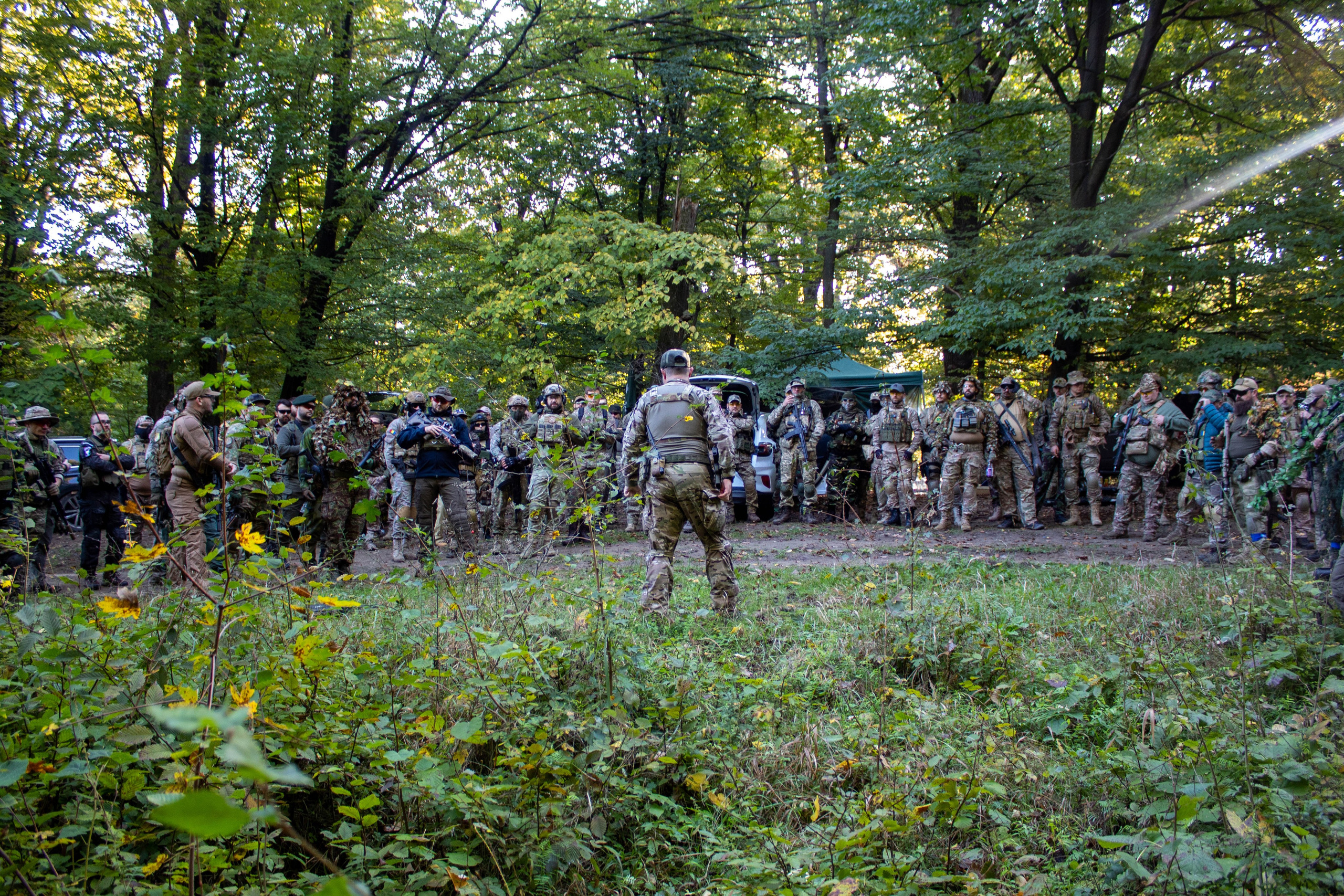 Airsoft team lined up in camouflage gear, preparing to enter a wooded field.
