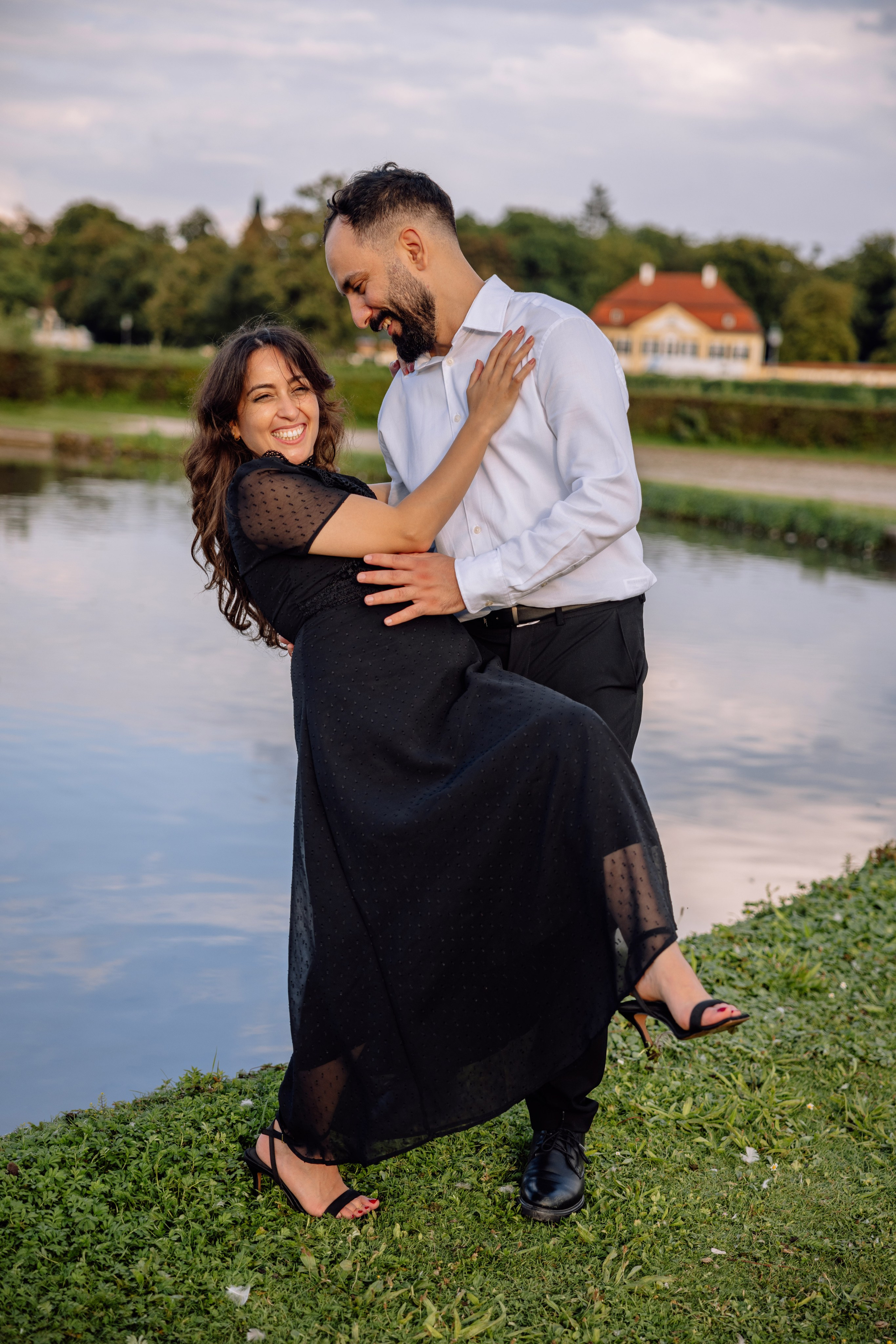 Verlobtes Paar umarmt sich und lacht zusammen vor dem Schloss Nymphenburg