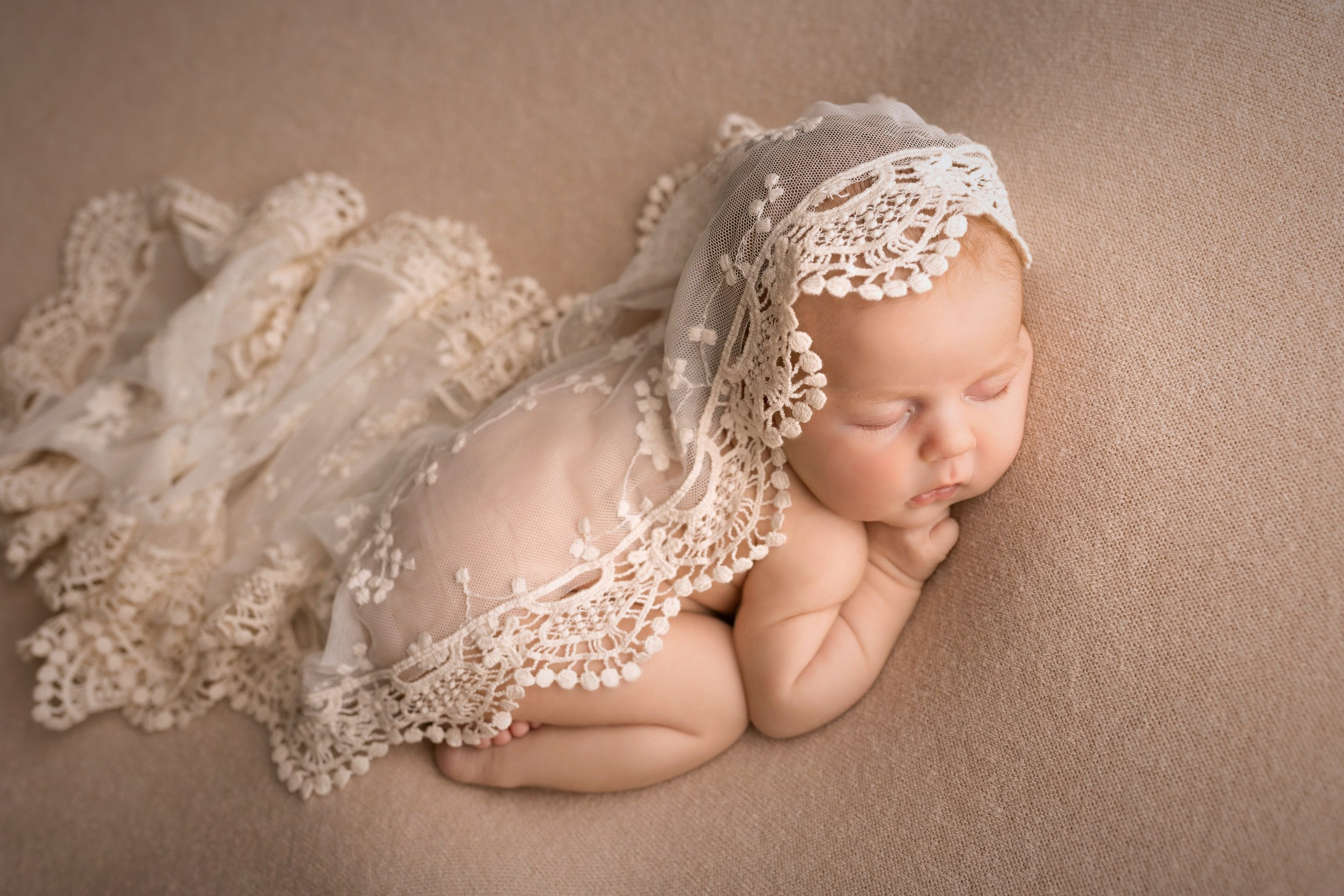 Newborn baby girl wrapped in soft veil, peaceful sleep