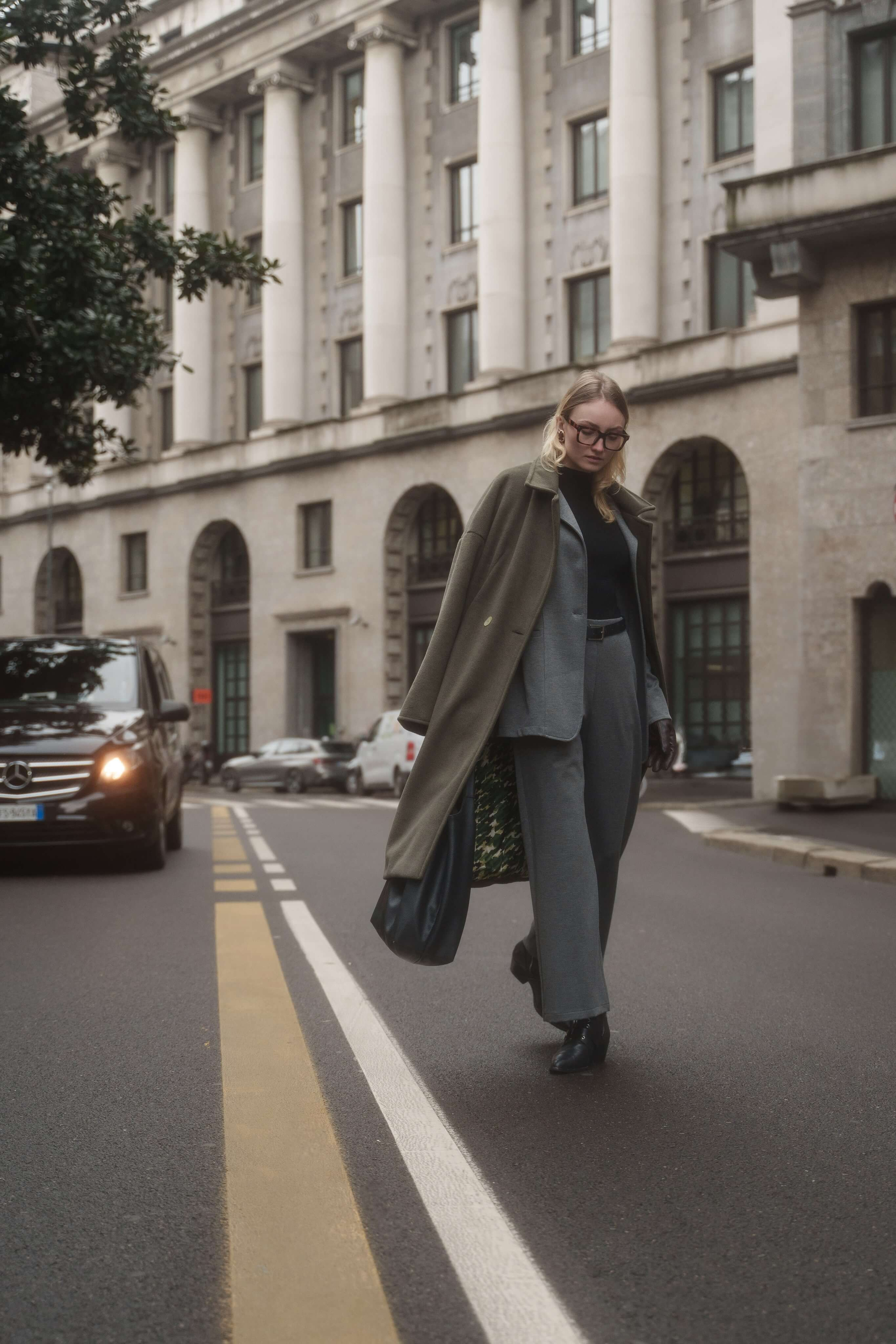 Stylish woman walking across a Milan street in a long coat and wide-leg trousers