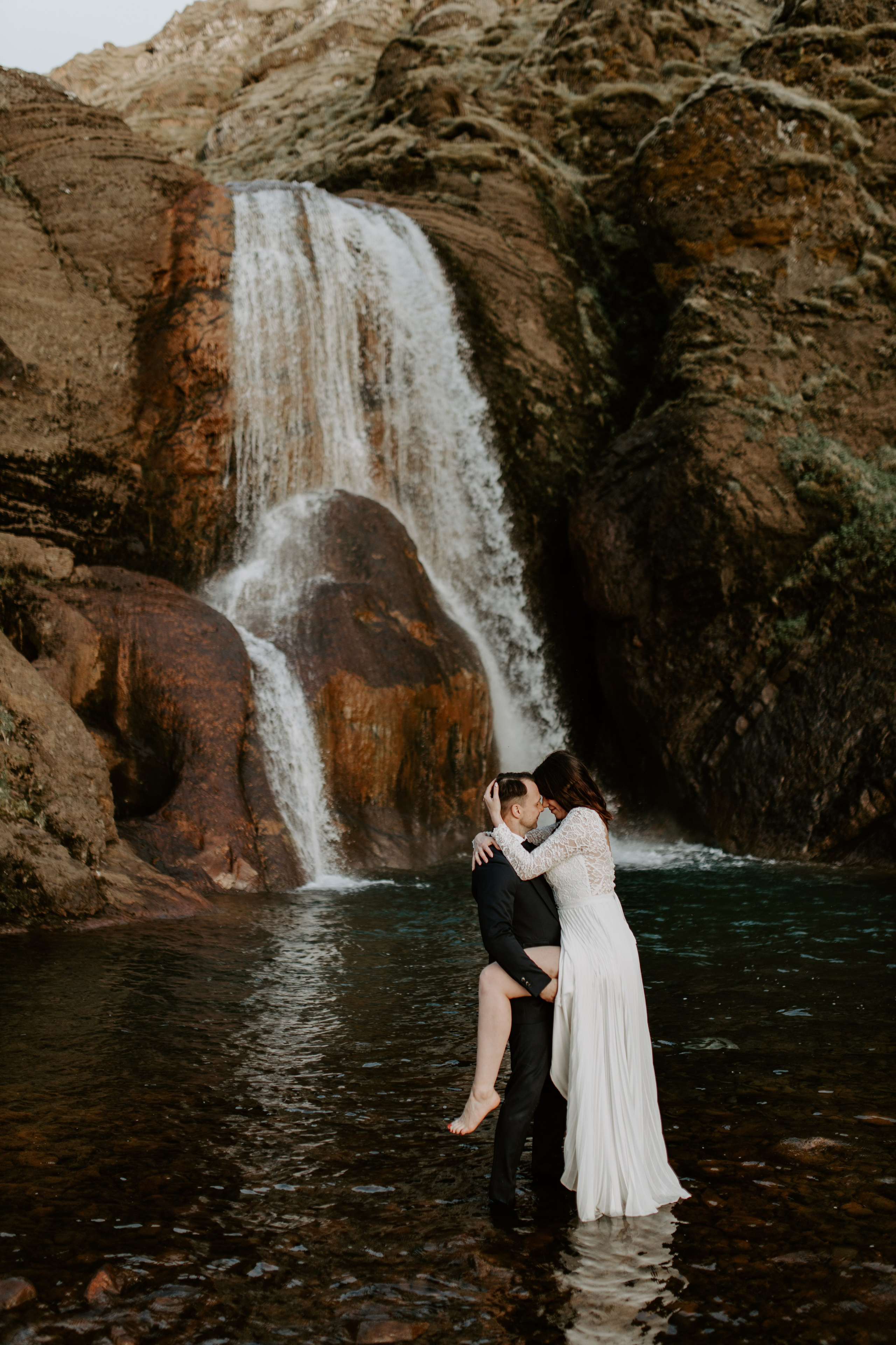Love in the wild—couple sharing a quiet moment in front of a majestic Icelandic waterfall.