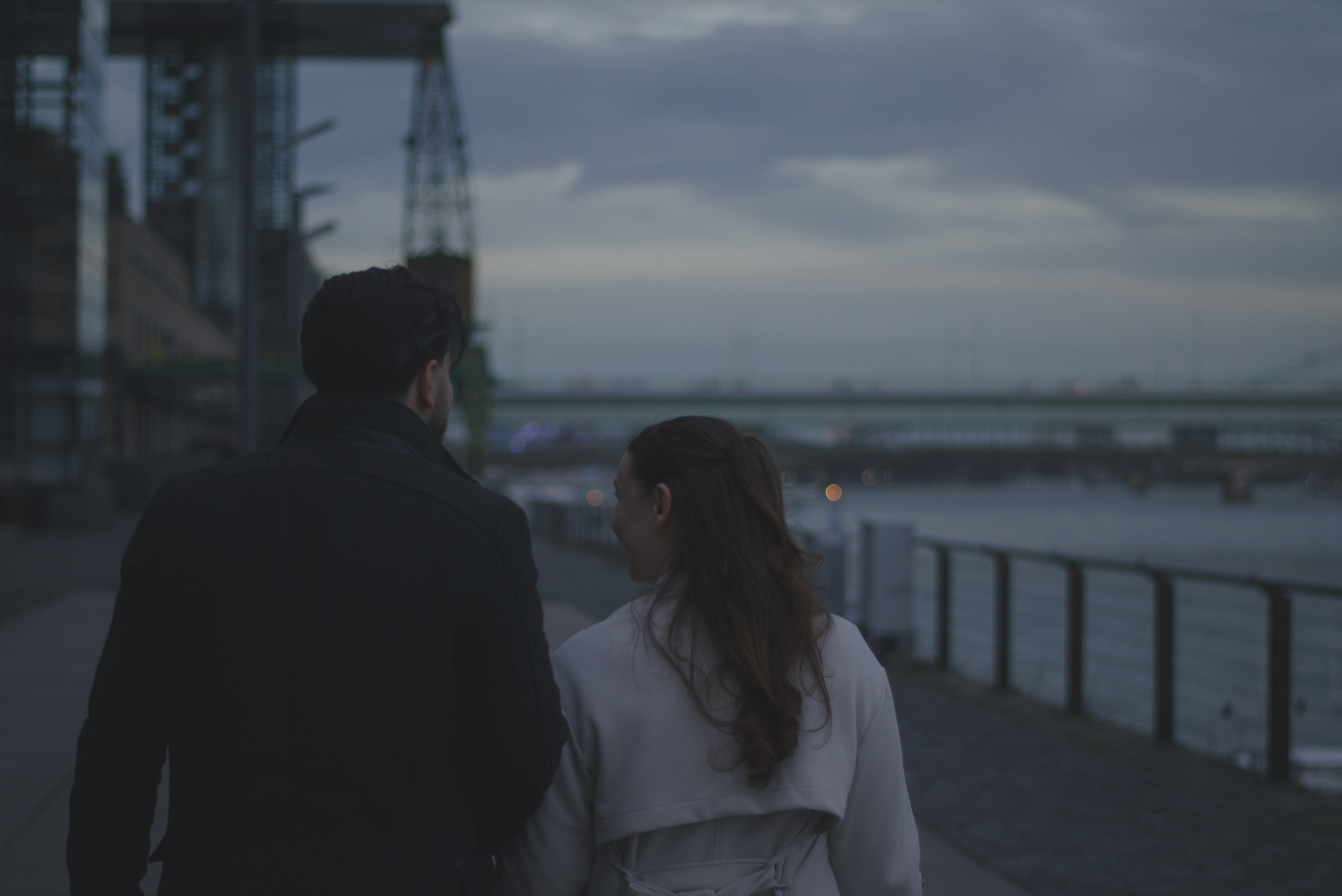 Foto eines verliebten Paares laufend von hinten zu sehen mit dem Fluss Rhein im Hintergrund