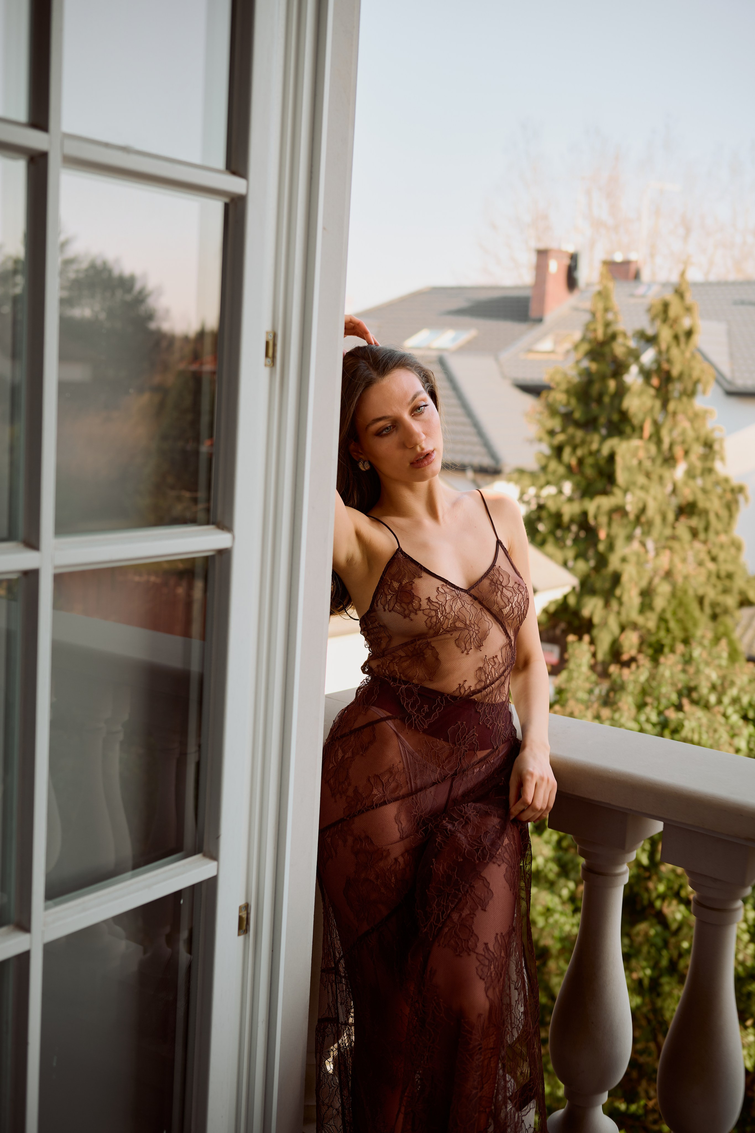 Zmysłowy portret na tle panoramicznego widoku – kobieta w eleganckiej koronkowej kreacji na balkonie luksusowej willi