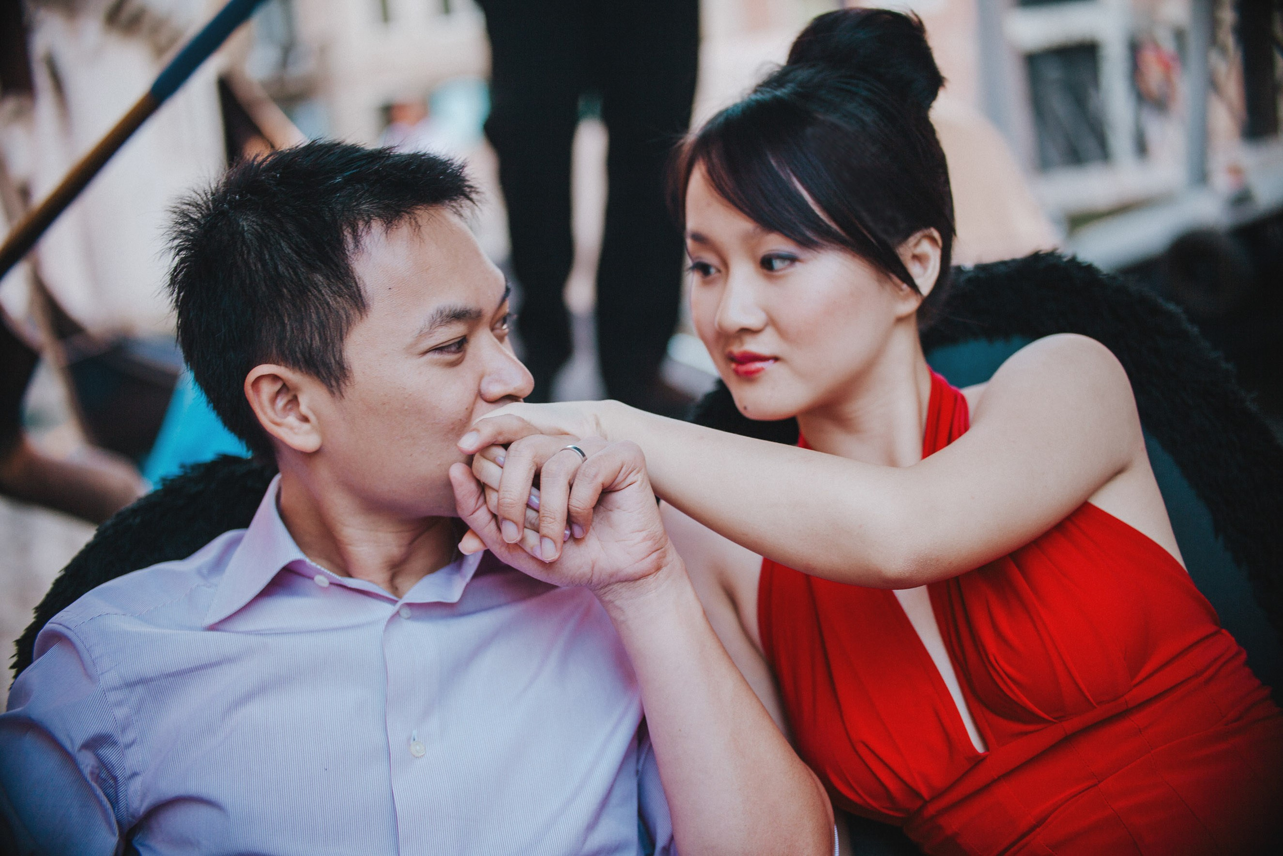 As their gondola makes its way into the historic canals of Venice a young Thai man kisses the hand of his bride-to-be who is wearing a striking red evening dress. 