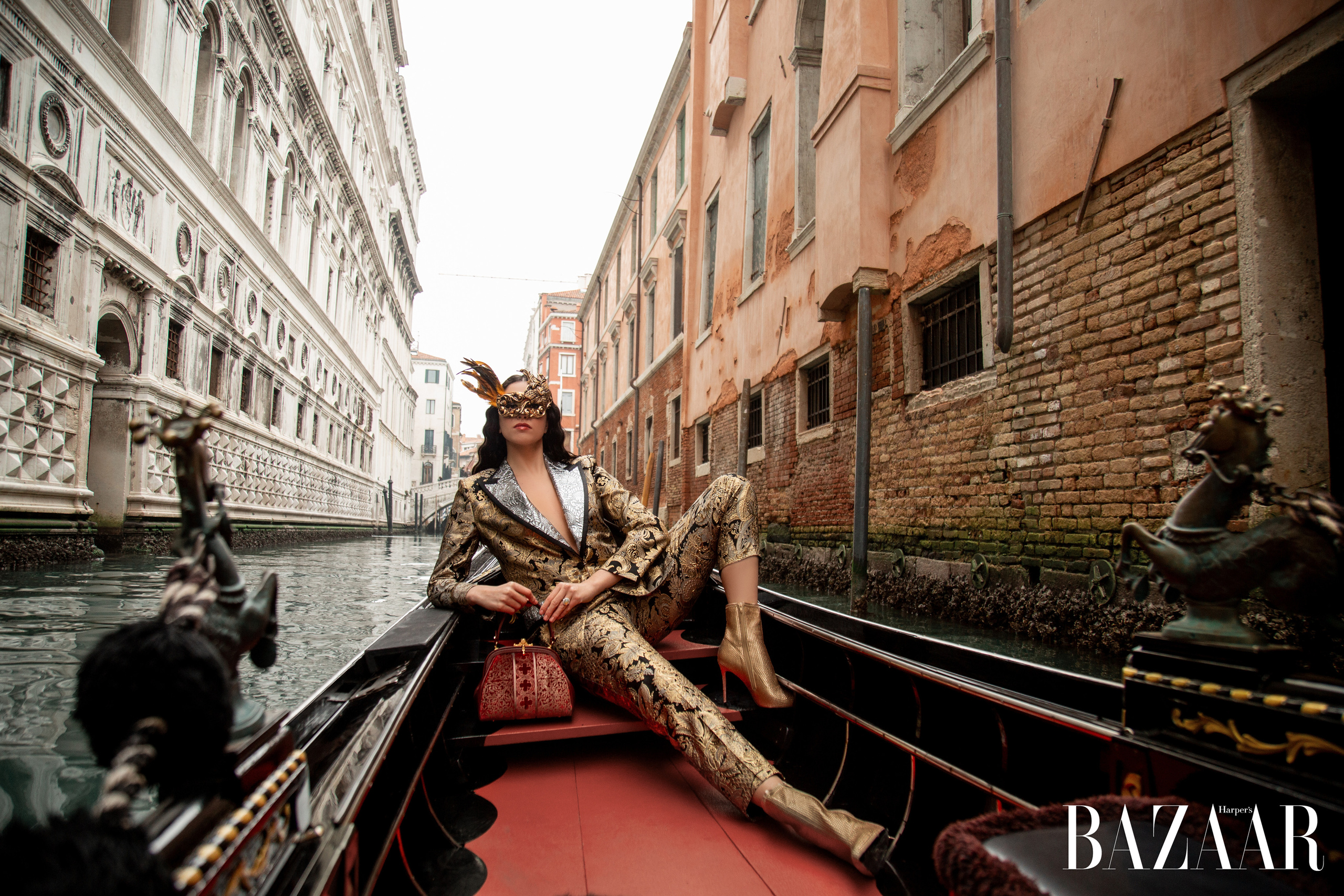 A beautiful girl in a gondola, against the backdrop of the Doge's Palace. Costume by Dolce Gabbana, she is wearing a traditional Venetian mask
