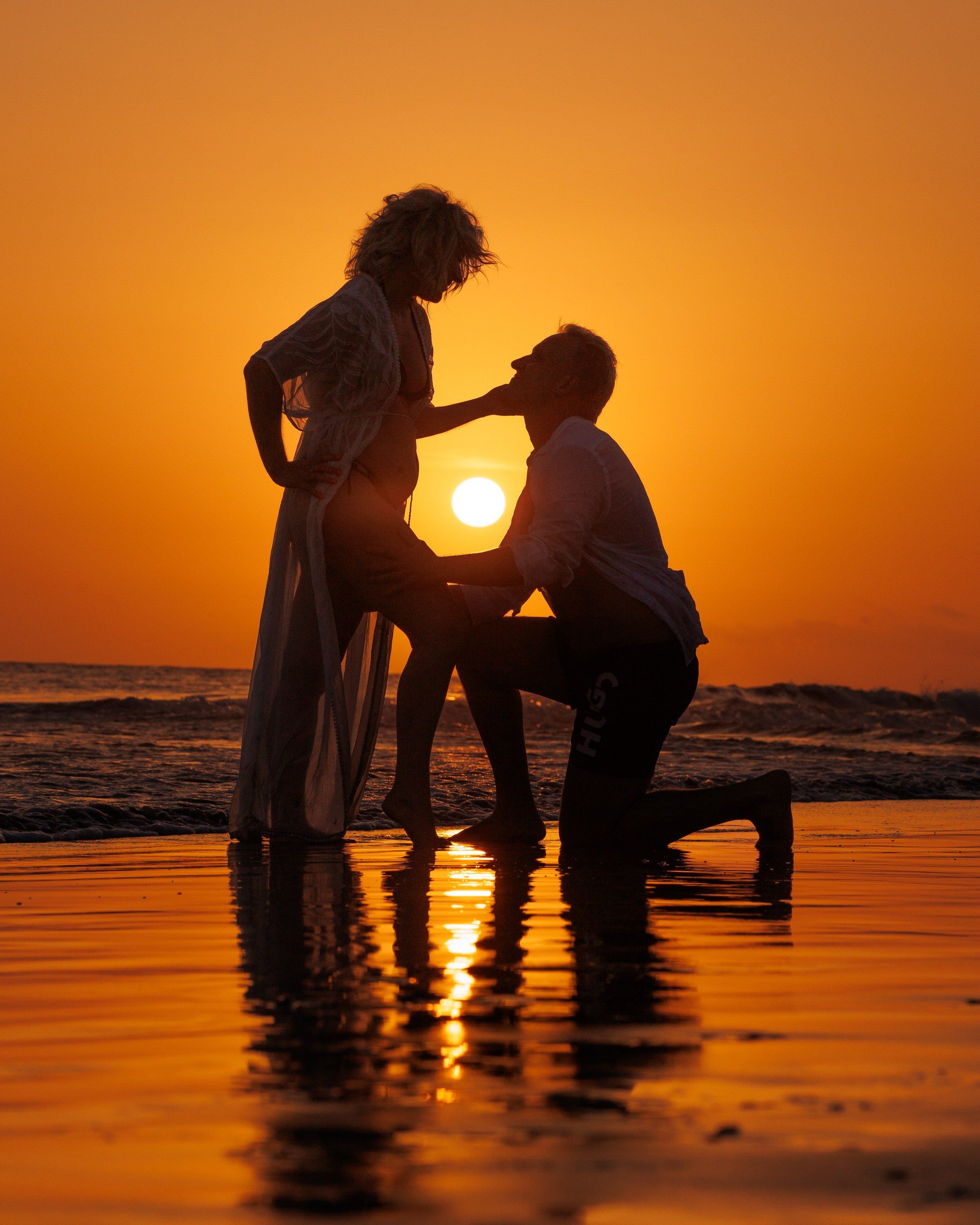 A couple is kneeling on the beach at sunset. Photographer Canarian Island