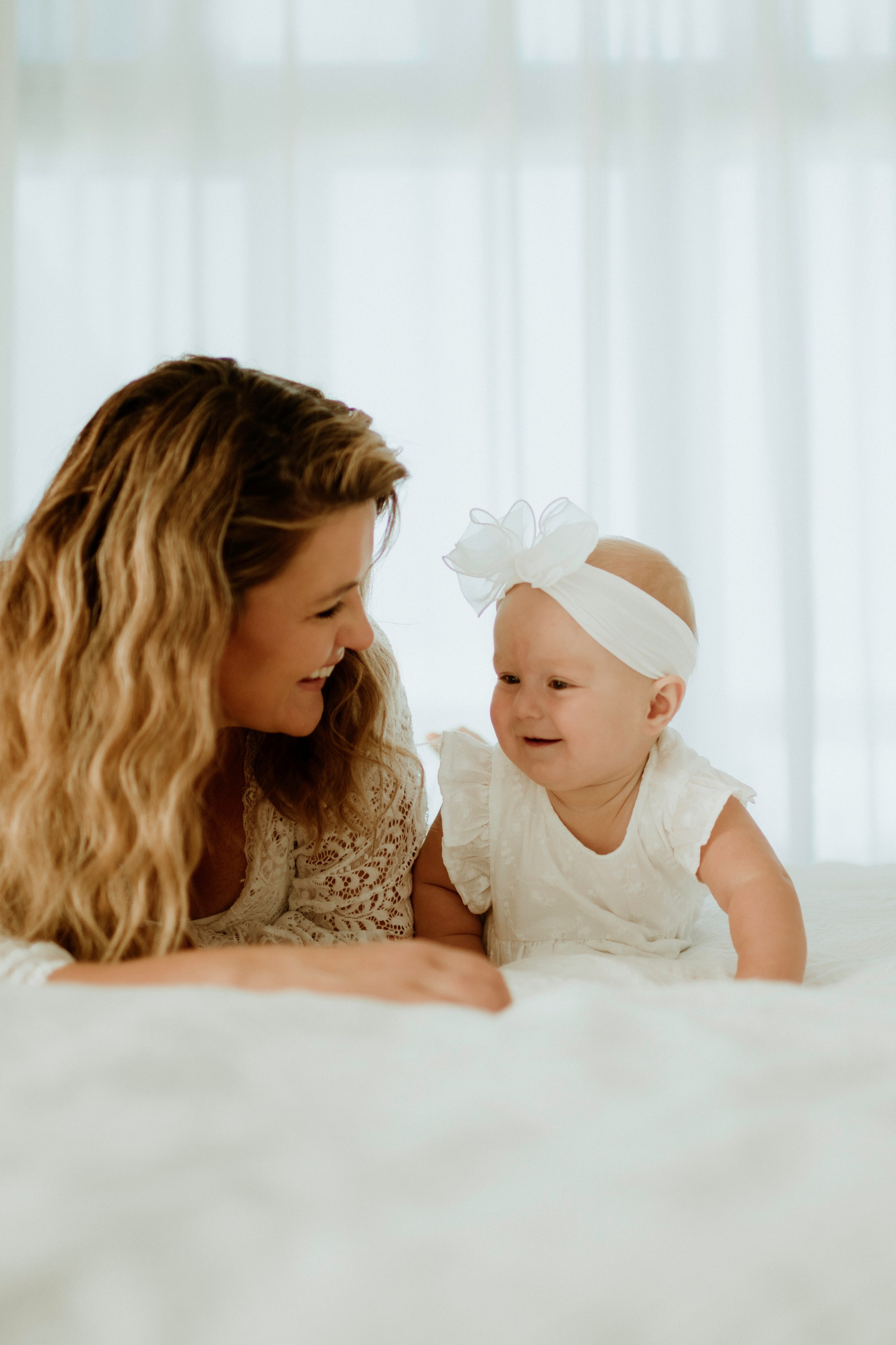 An enchanting outdoor maternity photoshoot at the client's house. The image features a radiant mother and her daughter, both elegantly dressed in white, against the backdrop of their home. The simplicity of their attire and the natural surroundings creates a timeless and intimate atmosphere. Book a personalized outdoor session with MD Studio to capture beautiful moments in the comfort of your own home
