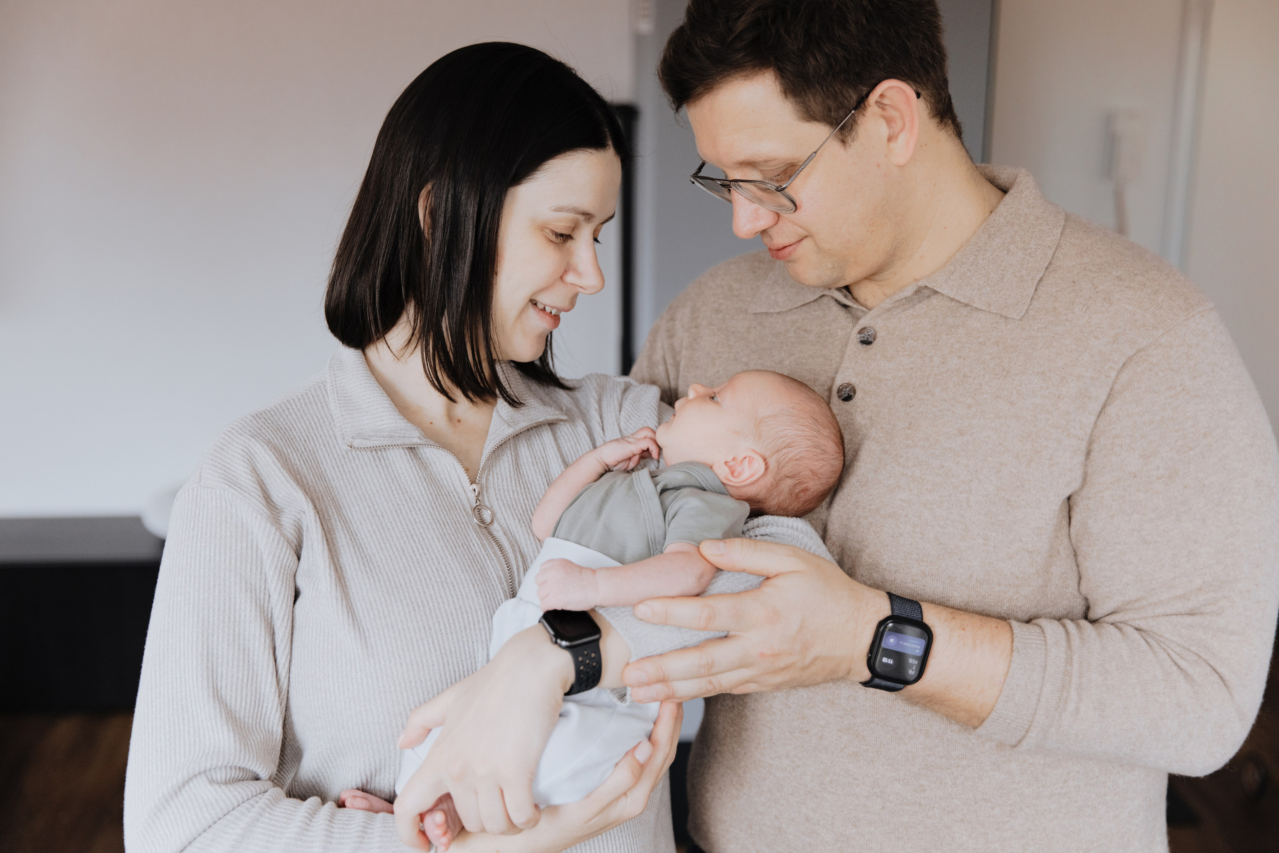 Mama und Papa halten ihr Neugeborenes liebevoll in den Armen.