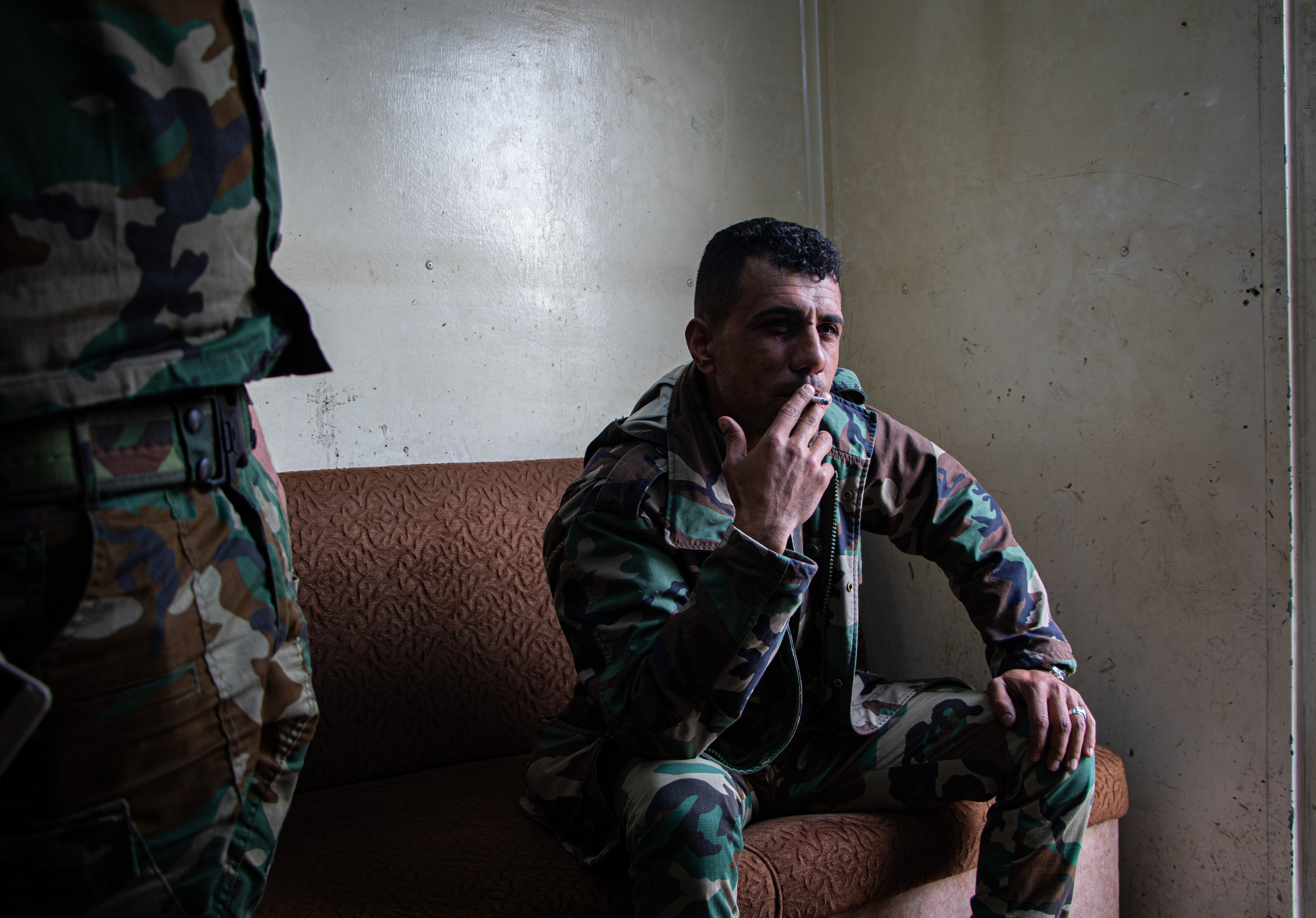 Un militaire yézidi fume une cigarette en surveillant l’entrée de la communauté yézidie.