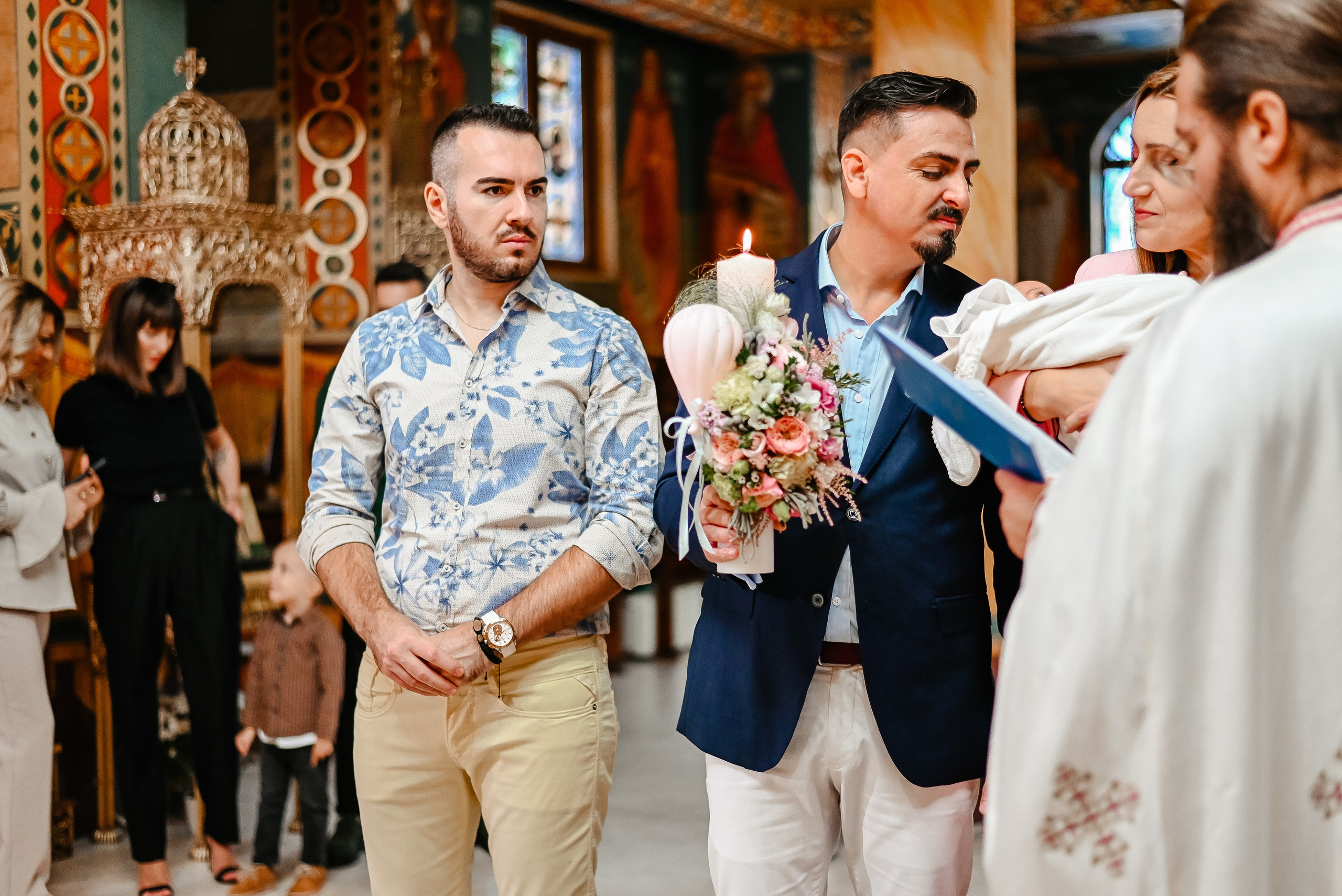 Părinții și nașii adunați în jurul cristelniței – imagine semnată Ana Maria Drăgan 