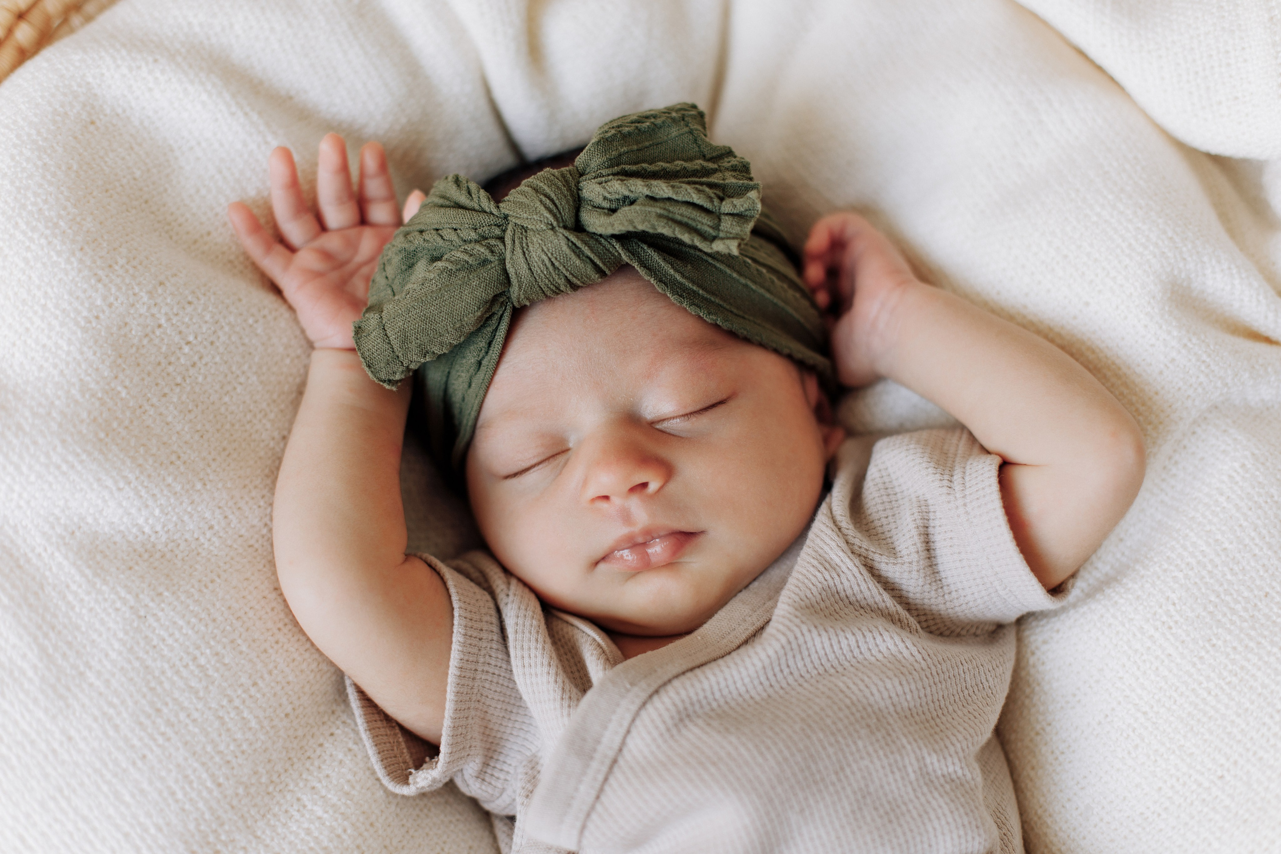 Baby liegt im Korb mit einer schönen Schleife am Kopf.