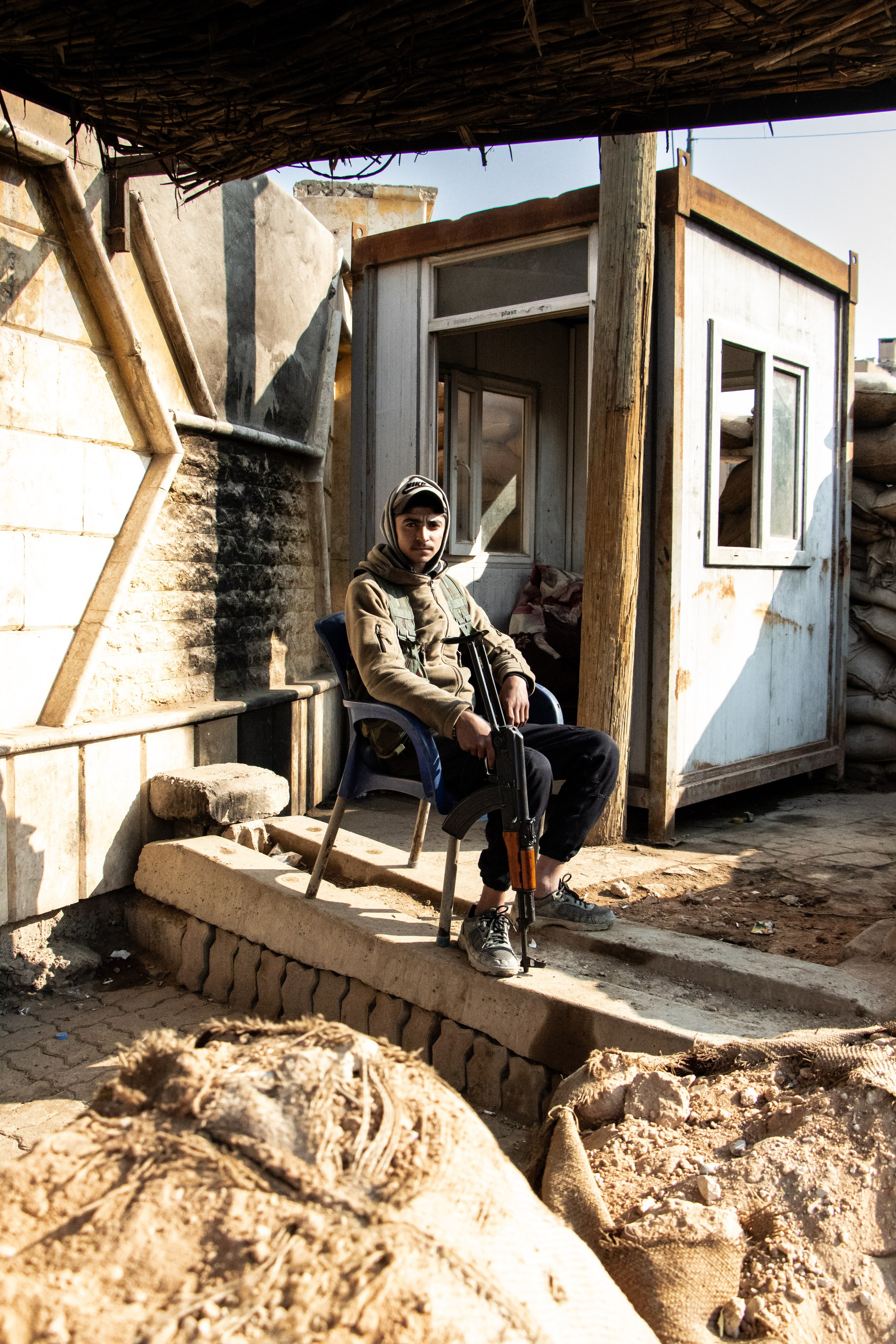 Un jeune garde surveille l'entrée d'une base des Forces Démocratiques Syriennes (FDS) à Raqqa.