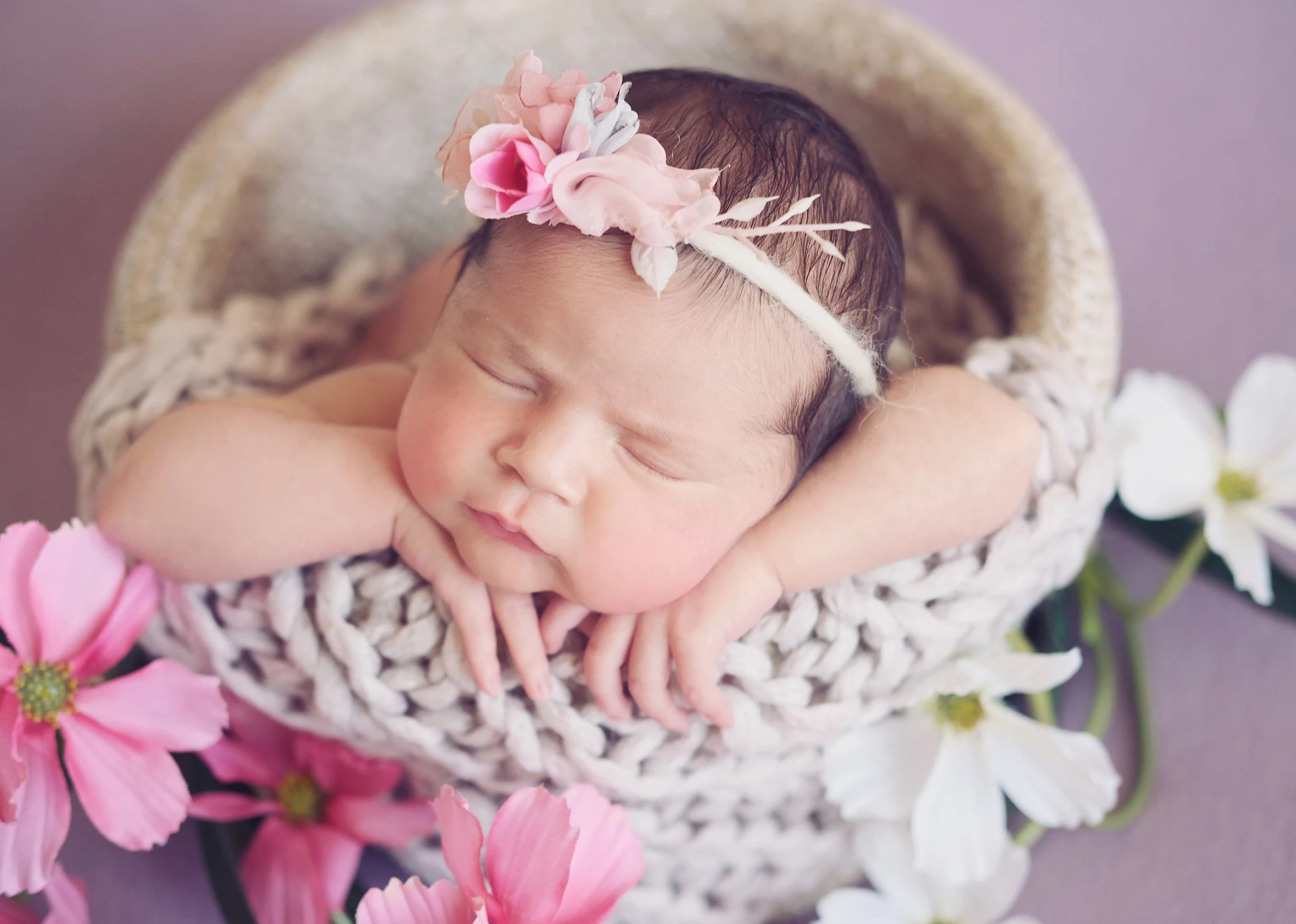 Newborn baby girl in white bucket surrounded by pink flowers