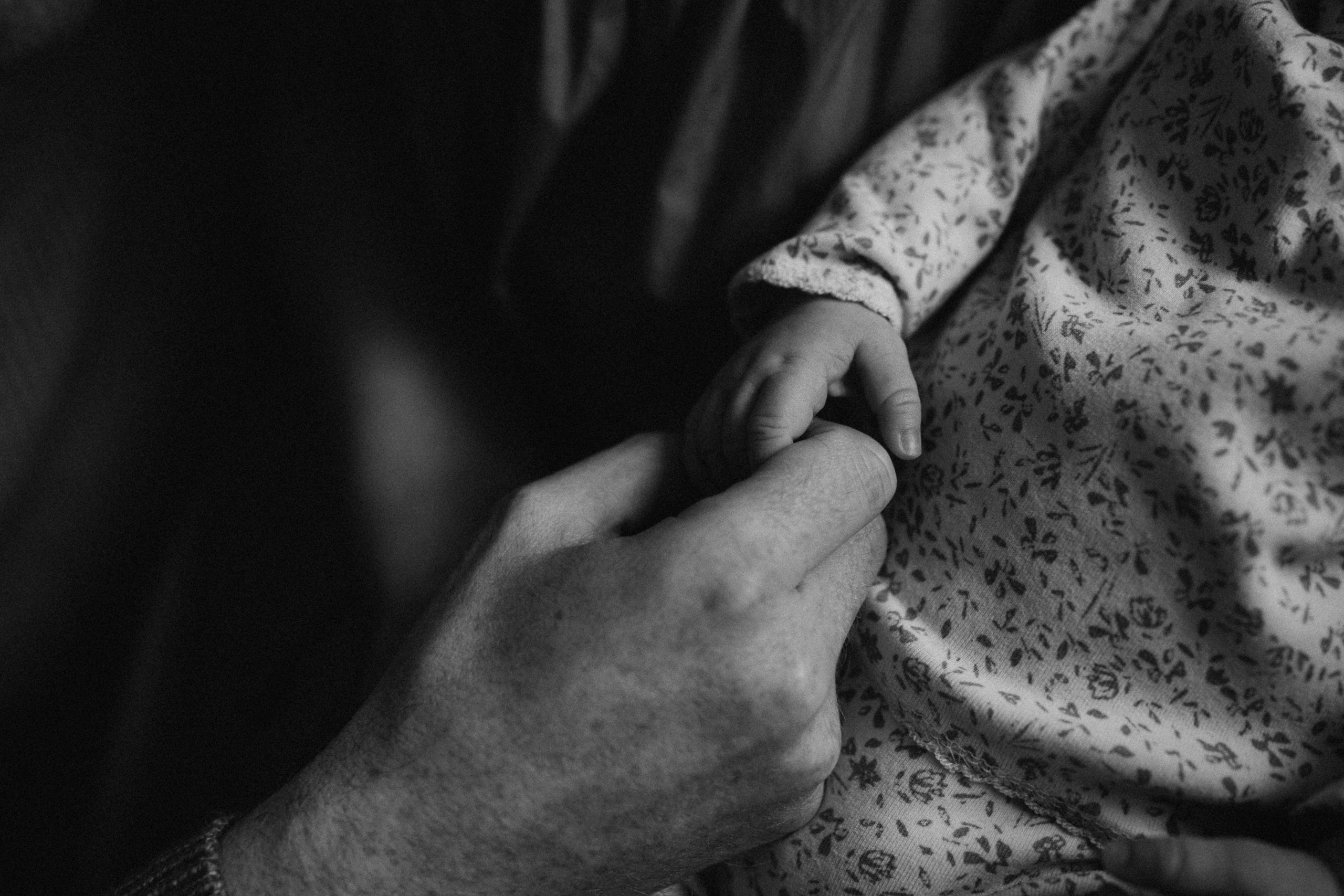 dad holds newborn baby hand