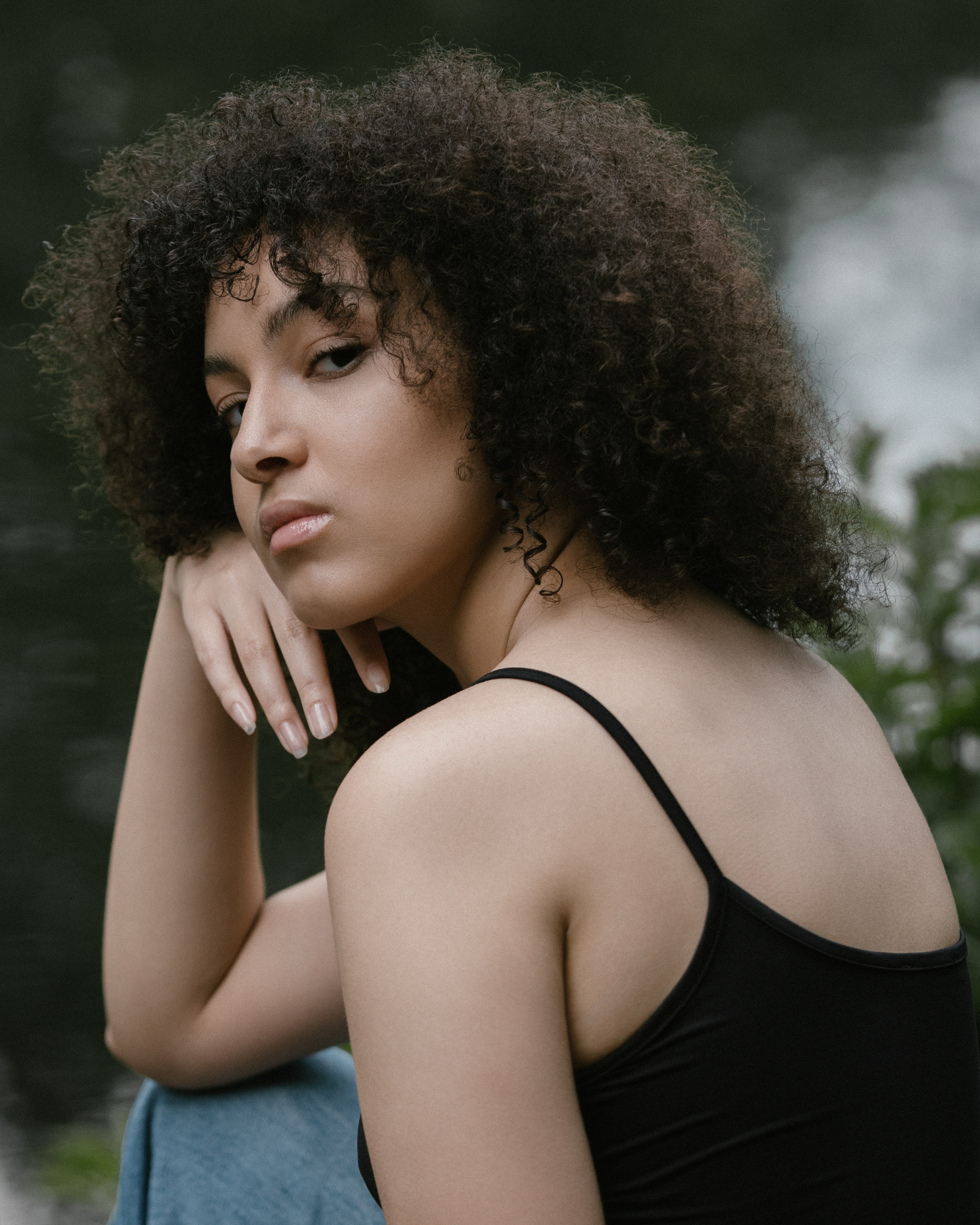 Portrait near water, woman in black top, looking over shoulder