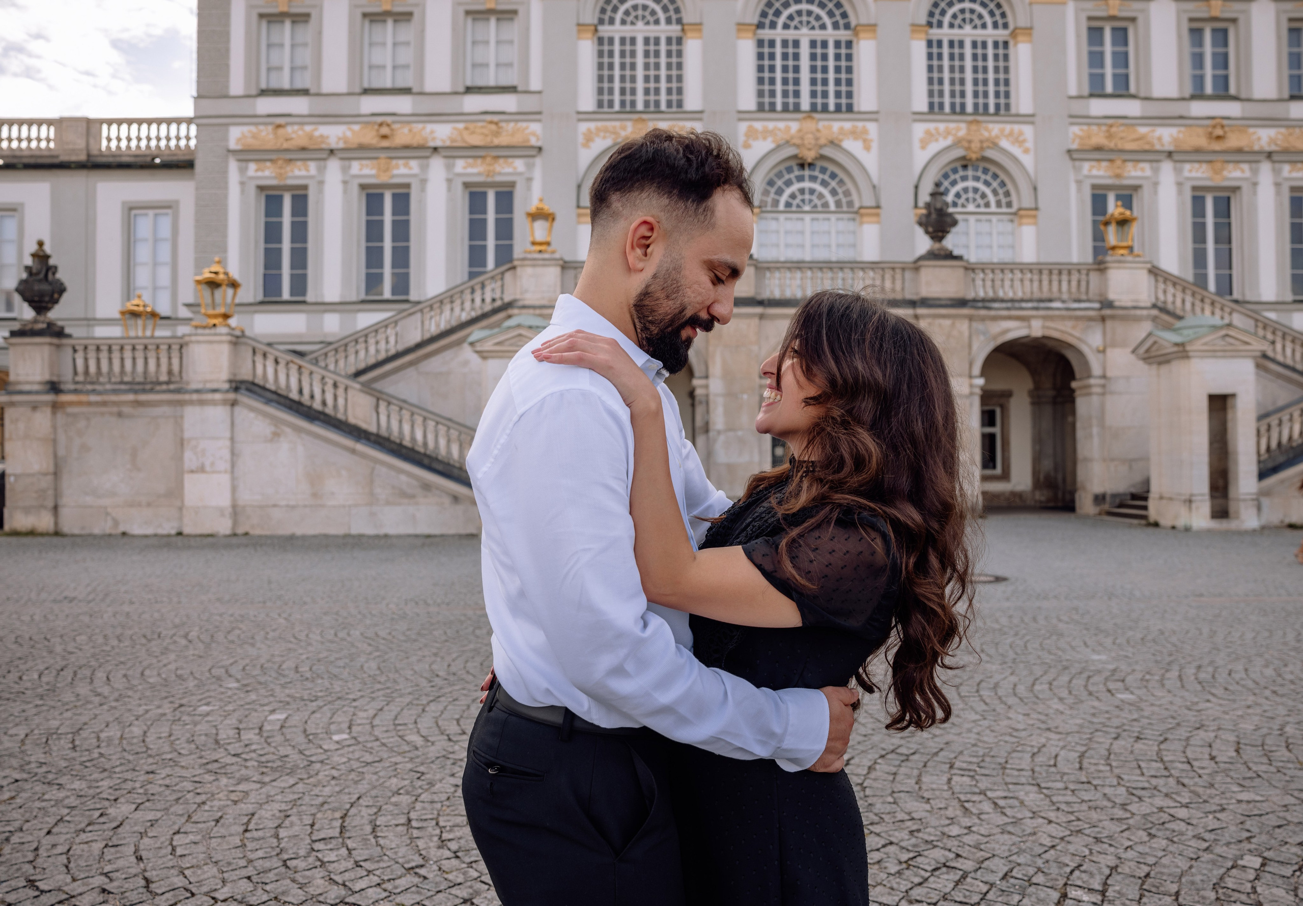 Paar lacht zusammen und umarmt sich vor dem Schloss Nymphenburg