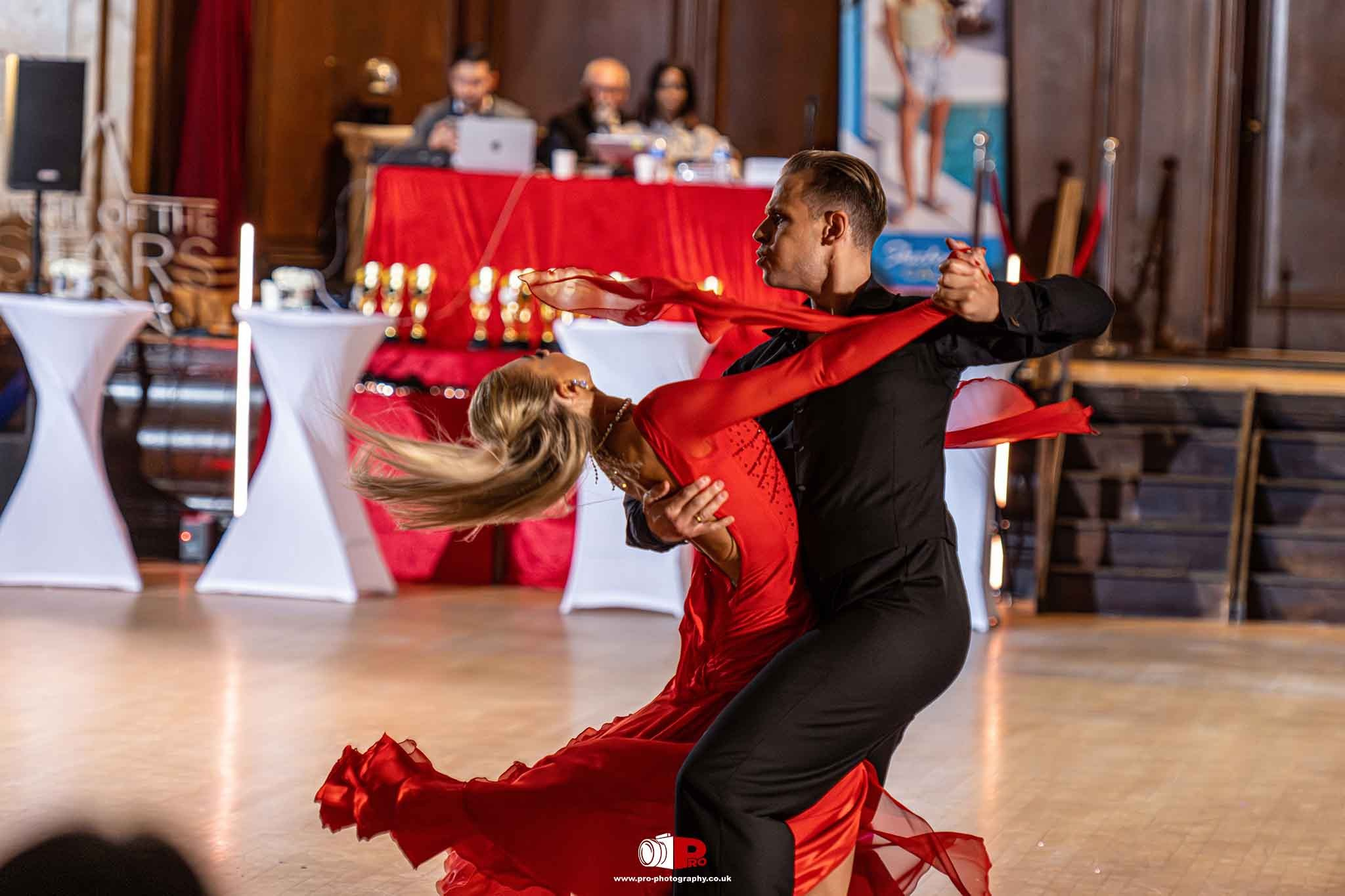 Ballroom dancers showcased a dramatic pose with a flowing red dress during a dance competition performance.