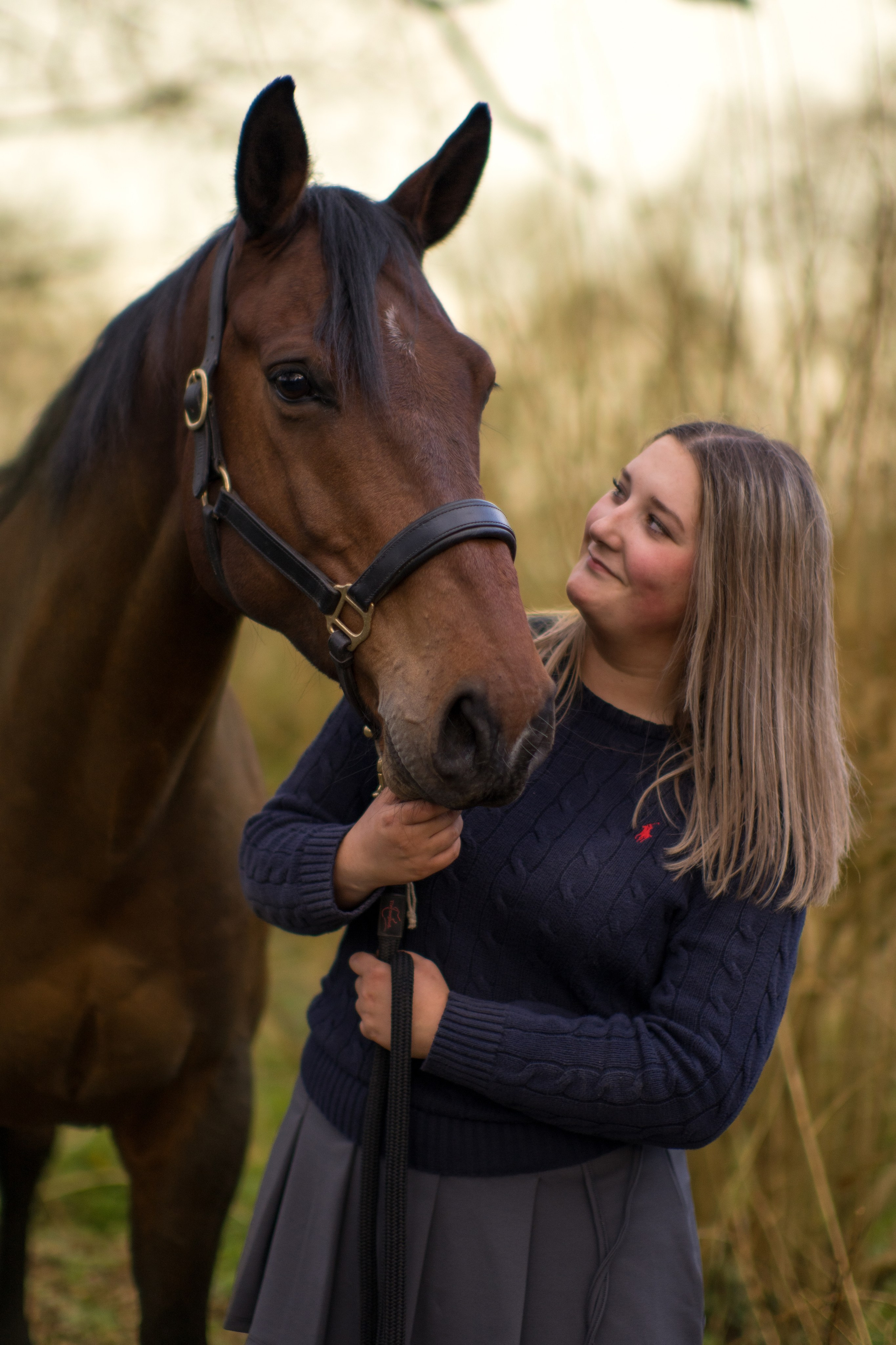 Young girl walking with a brown pony at sunset in Leicestershire countryside