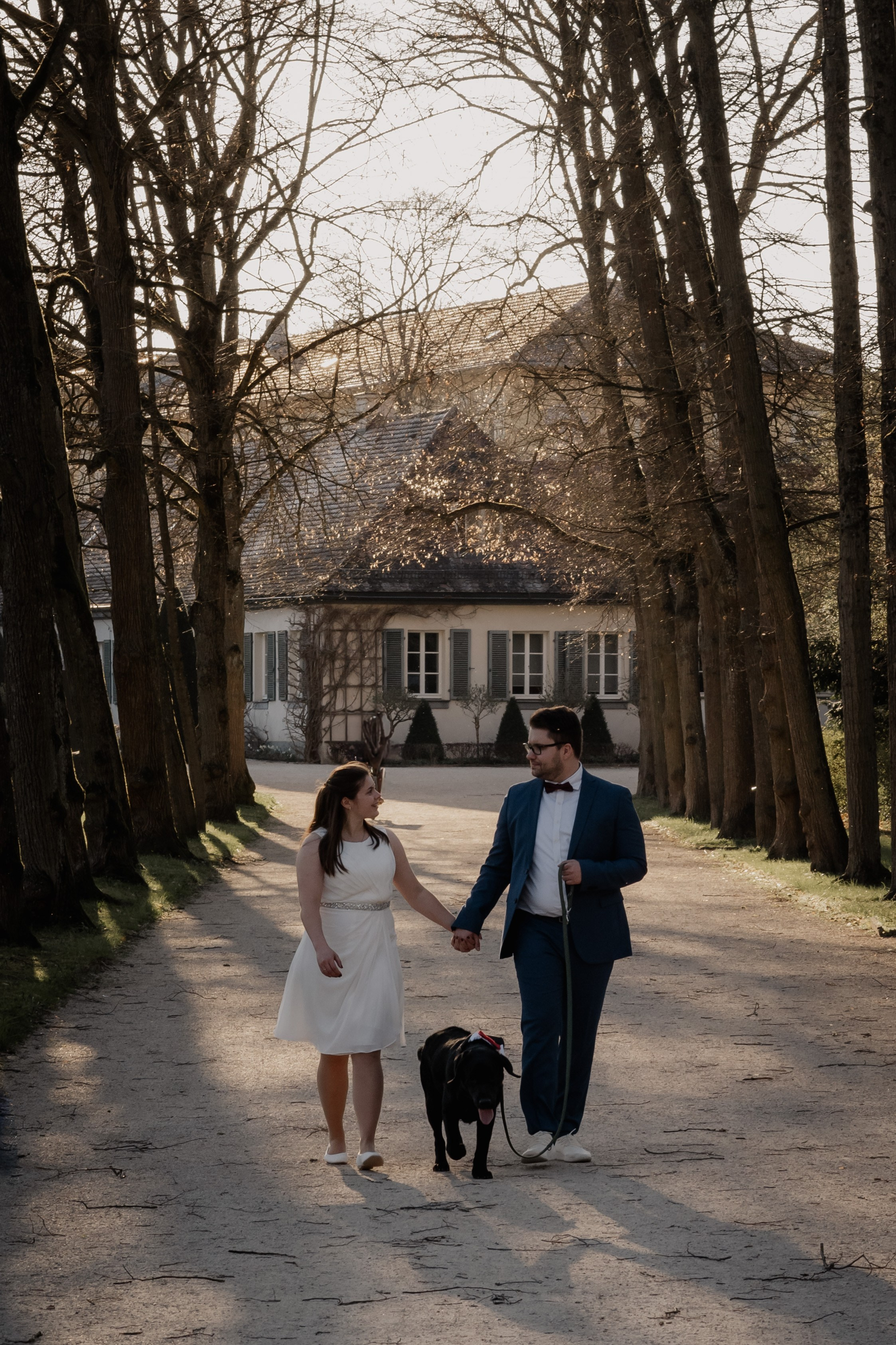 Ein Hochzeitspaar geht mit einem Hund im Hofgarten Ansbach.