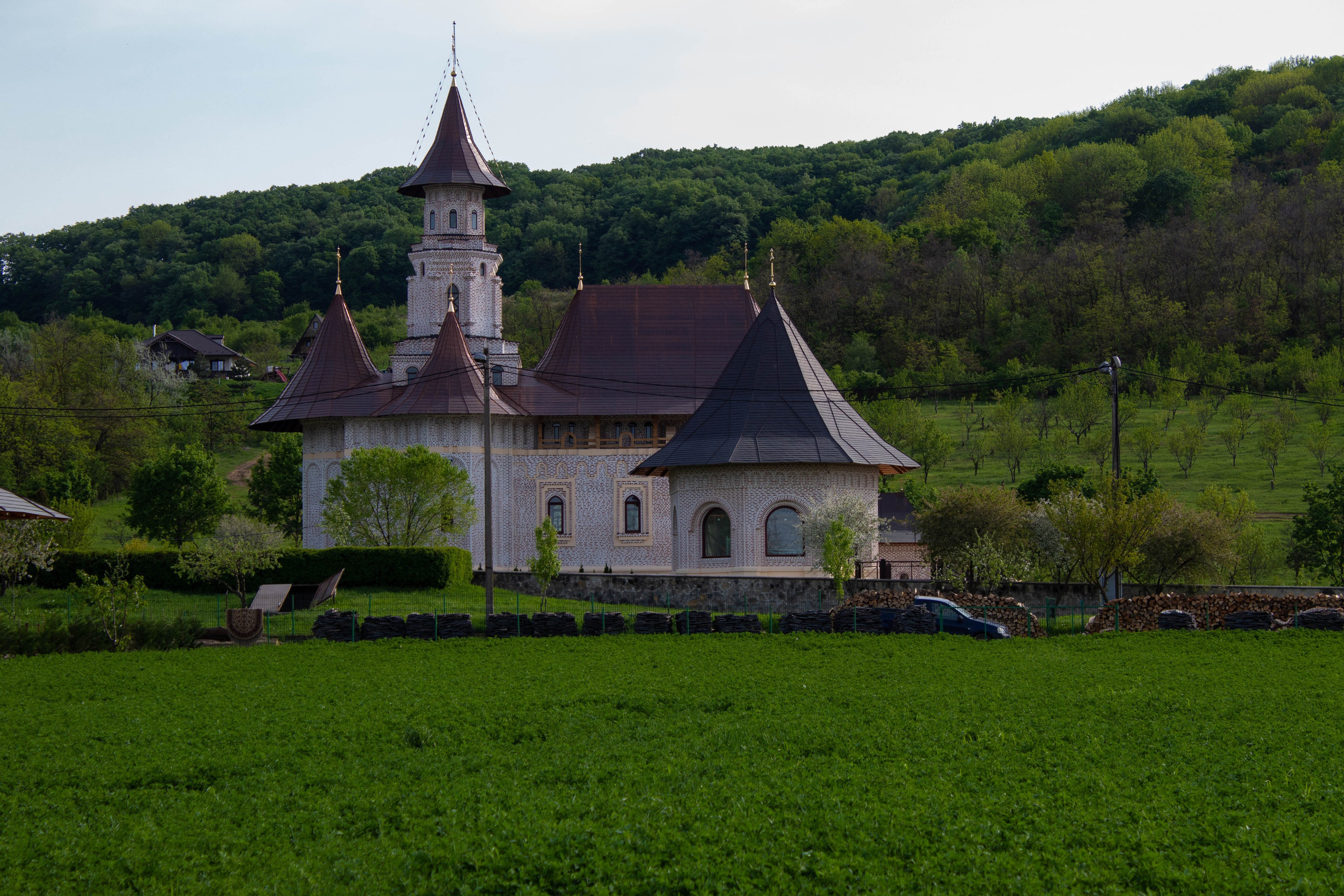 Small rural church with a red roof sitting on a grassy hillside in the countryside.