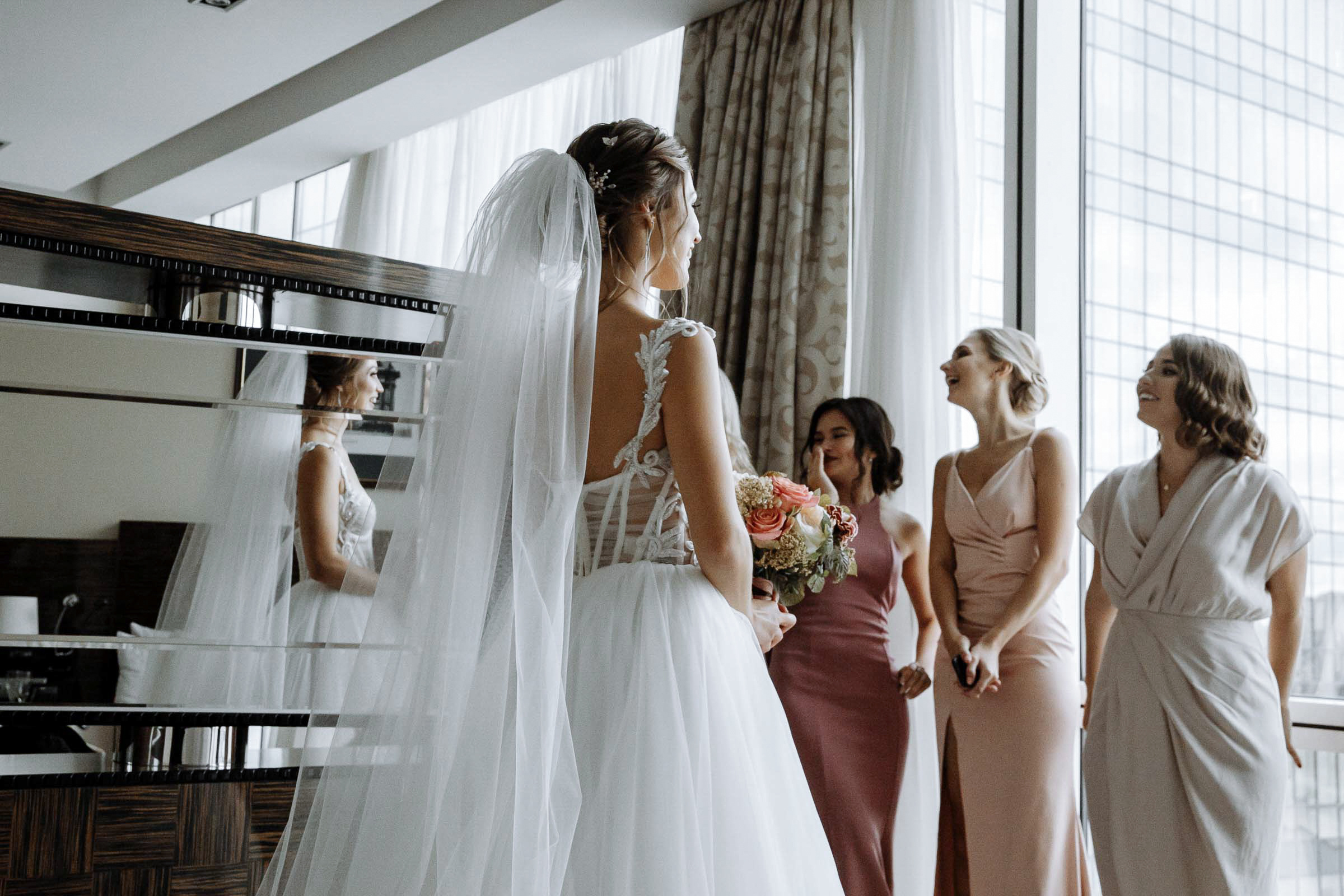 Bridesmaids in room reflected by mirror with bride, by Tanya Bodgan, Bude wedding photography.  